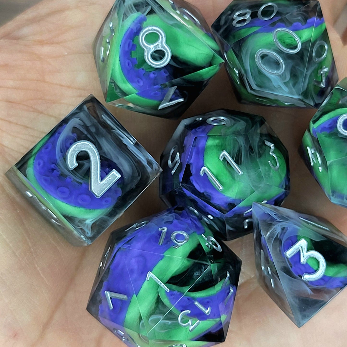 Handcrafted sharp edge resin dice featuring eerie green and purple tentacles suspended in dark transparent resin, surrounded by ghostly white mist and finished with metallic silver numbers