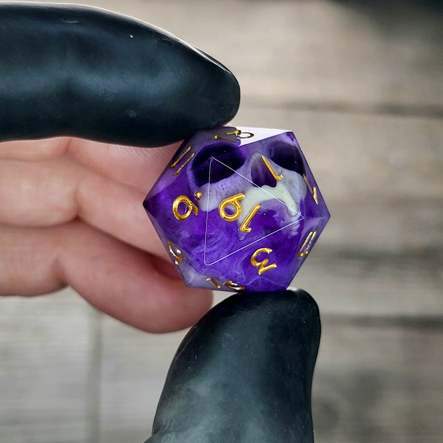 This is a single set of one D20 DnD die with a light brown skull inside , purple resin and gold numbers