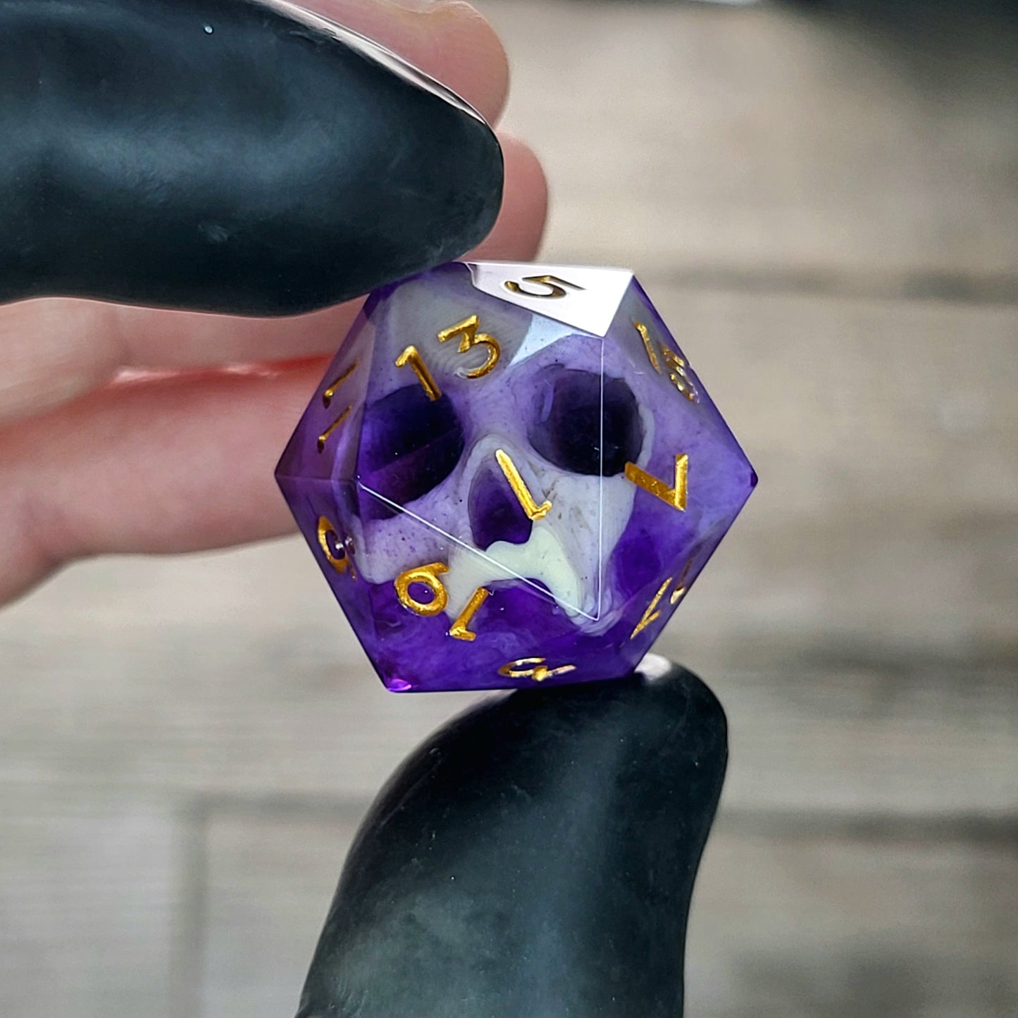 This is a single set of one D20 DnD die with a light brown skull inside , purple resin and gold numbers