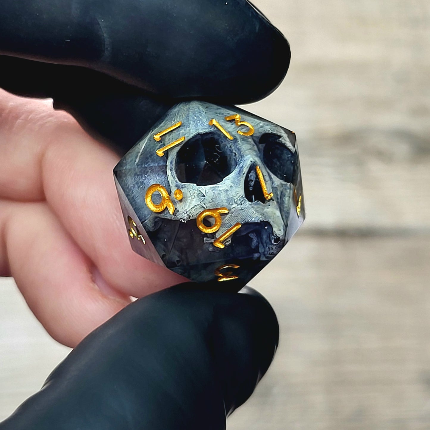 This is a single set of one D20 DnD die with a grey stone skull inside , black resin and gold numbers