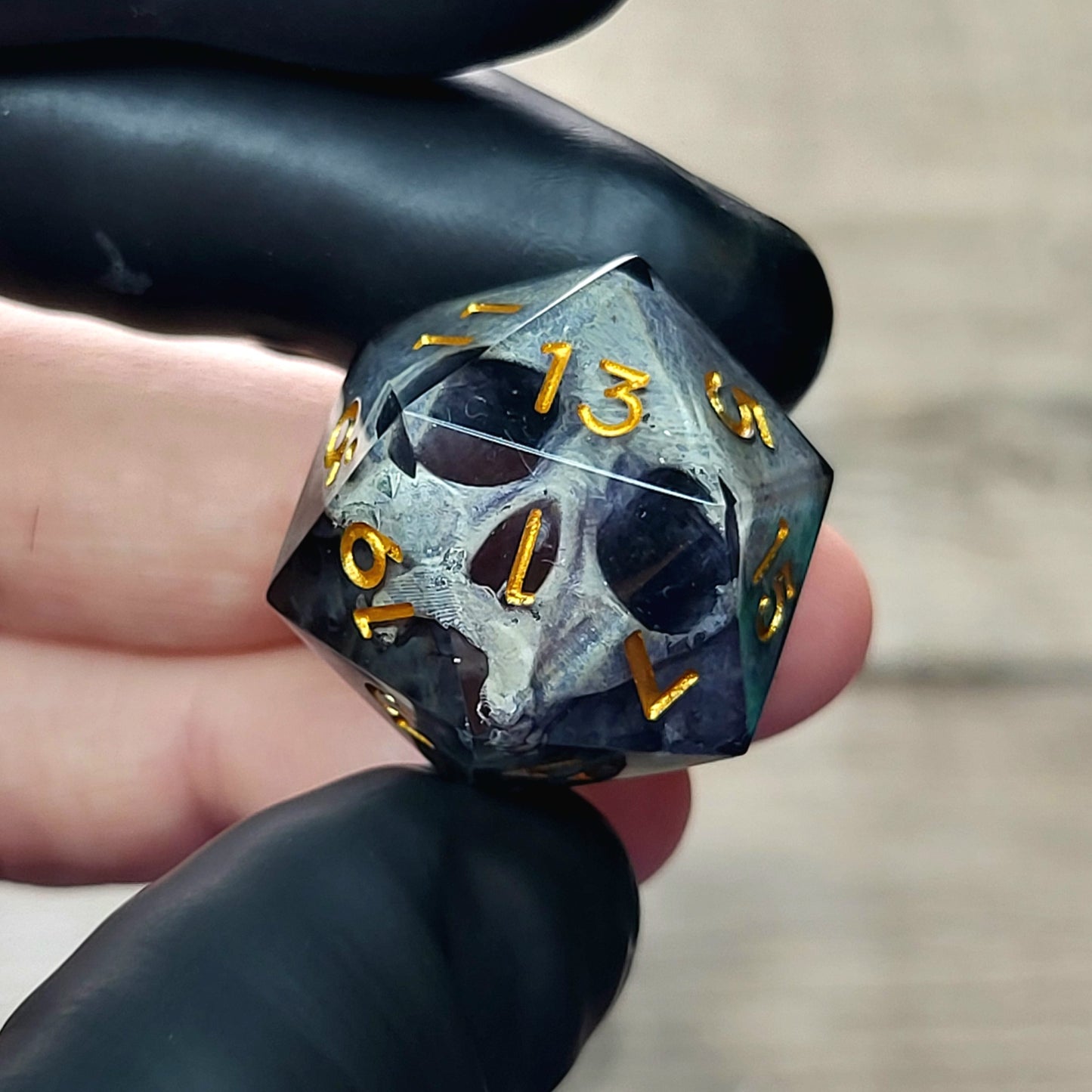 This is a single set of one D20 DnD die with a grey stone skull inside , black resin and gold numbers
