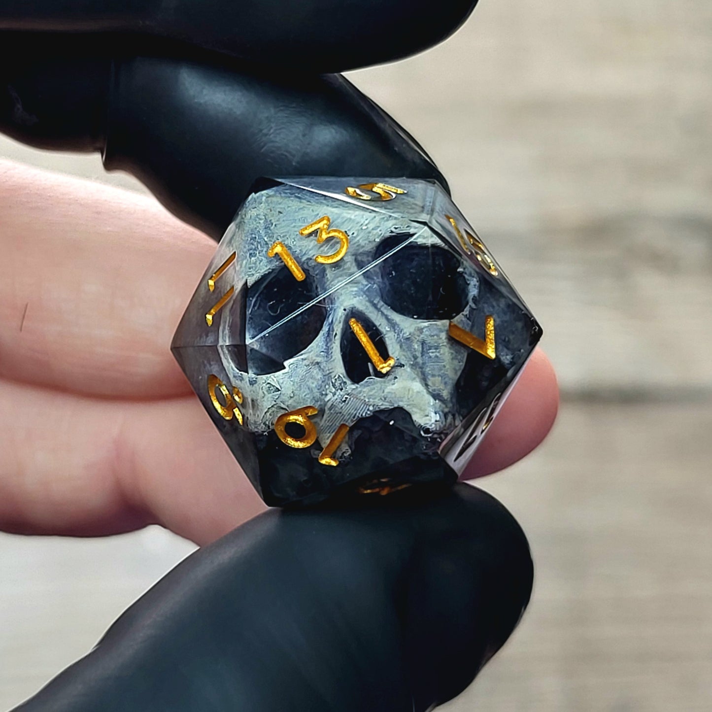This is a single set of one D20 DnD die with a grey stone skull inside , black resin and gold numbers