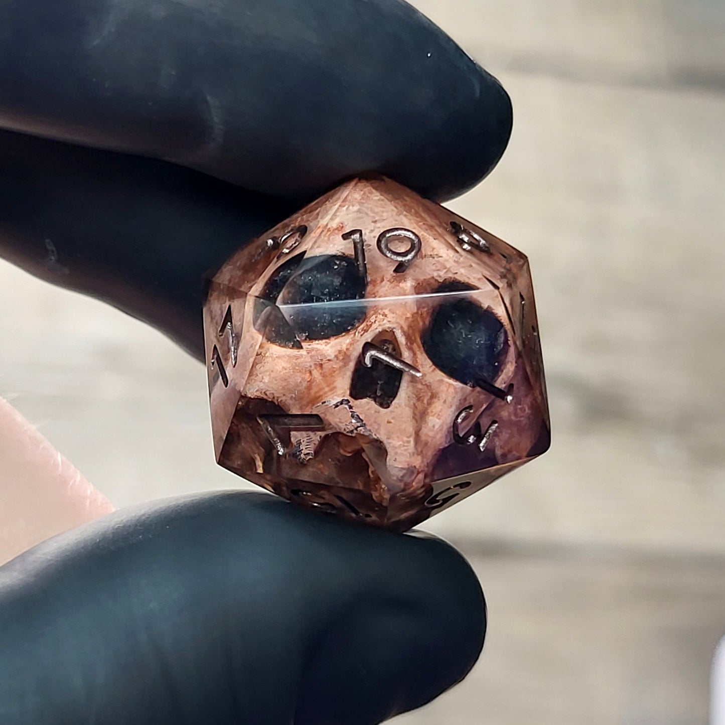 This is a single set of one D20 DnD die with a light brown skull inside ,black resin and dark bronze numbers