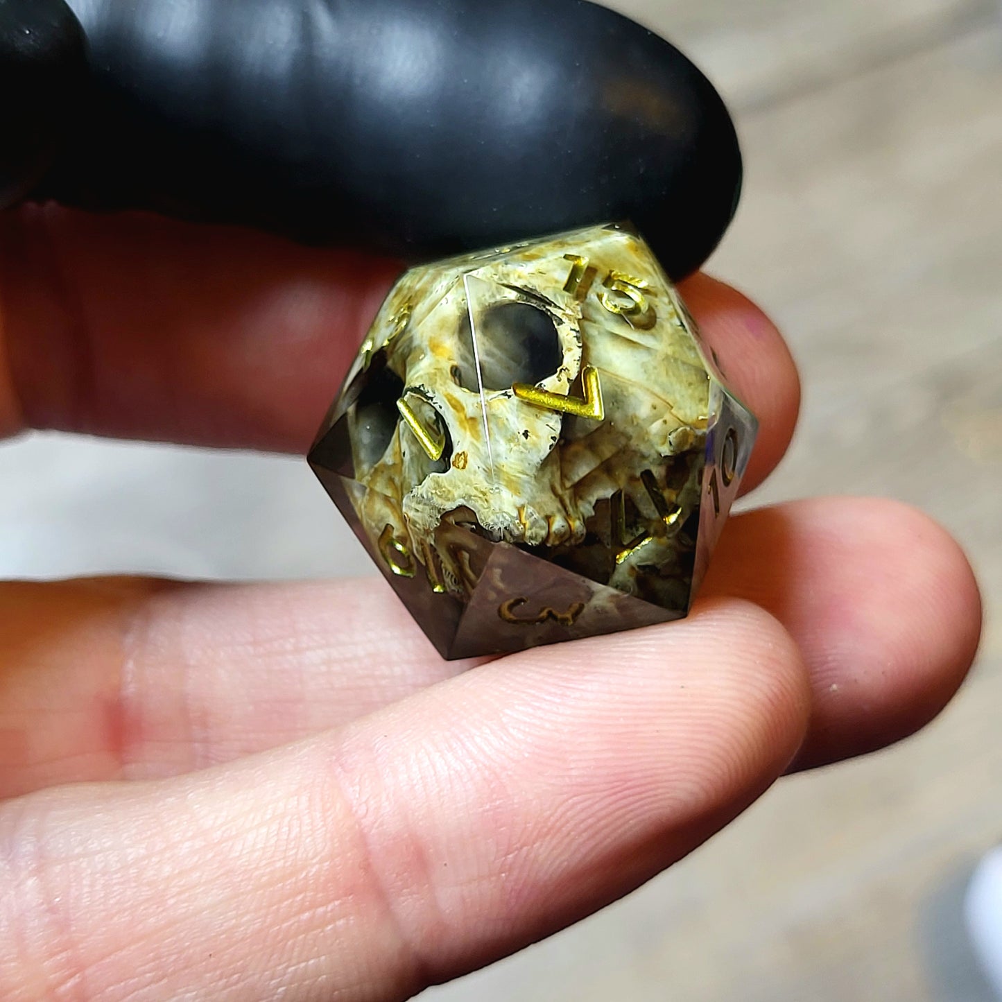 This is a single set of one D20 DND die with a light brown skull inside ,black resin and green gold numbers