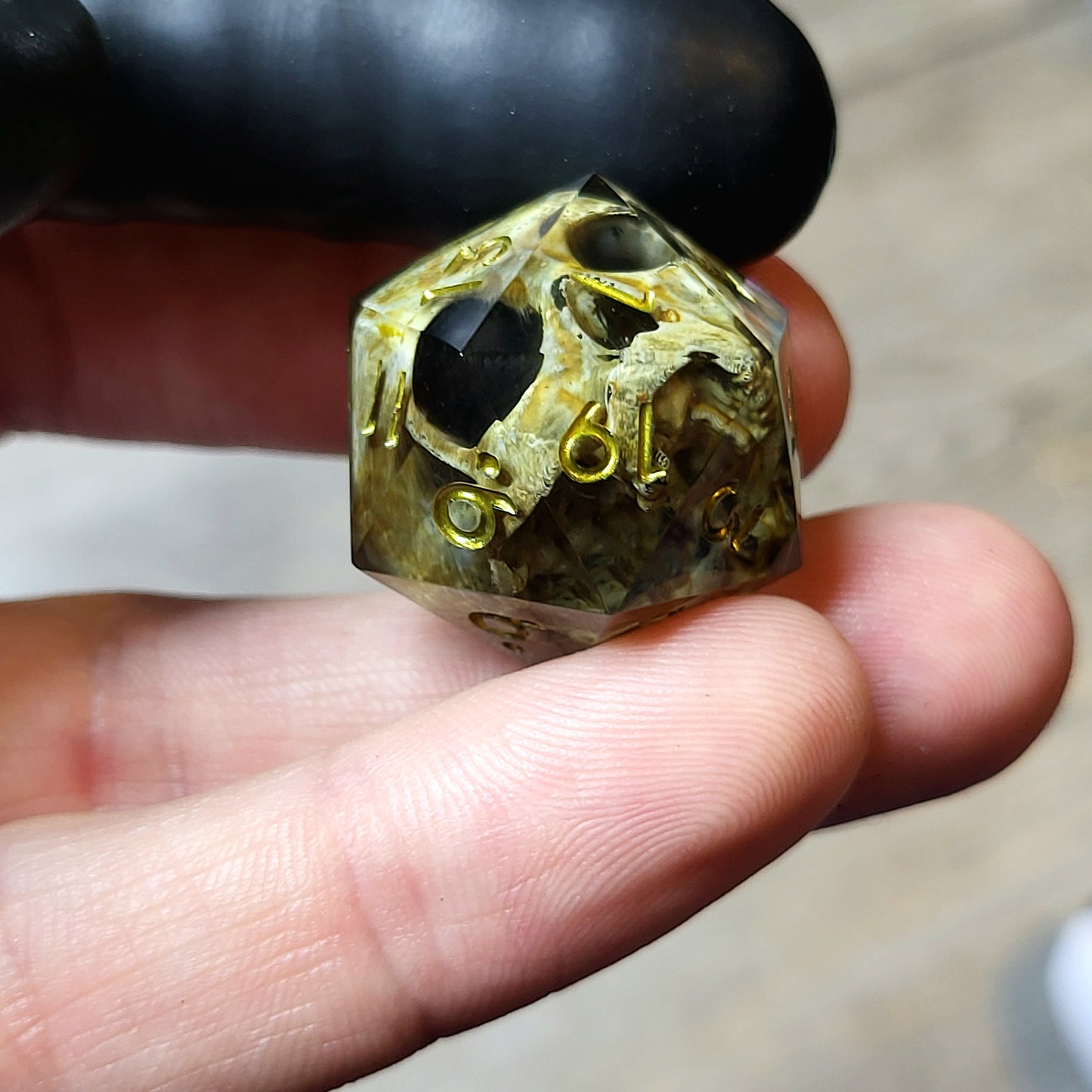 This is a single set of one D20 DND die with a light brown skull inside ,black resin and green gold numbers