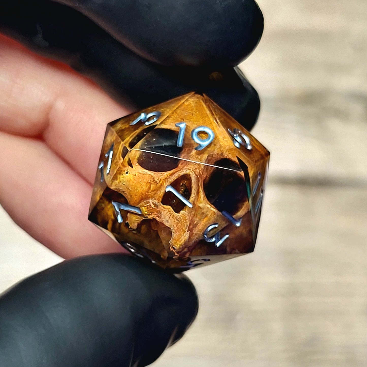 This is a single set of one D20 DnD die with a light brown skull inside , black resin and silver numbers