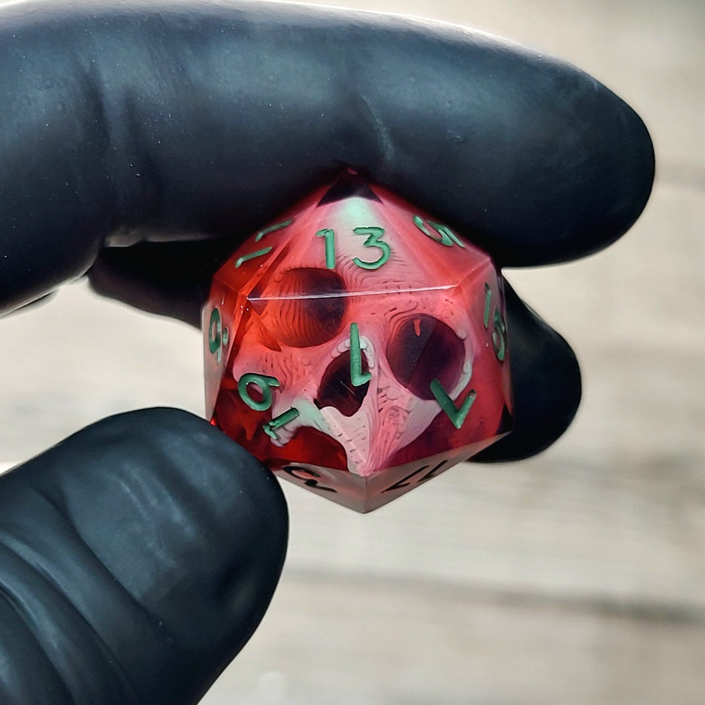 This is a single set of one D20 DnD die with a light green skull inside , red resin and green numbers