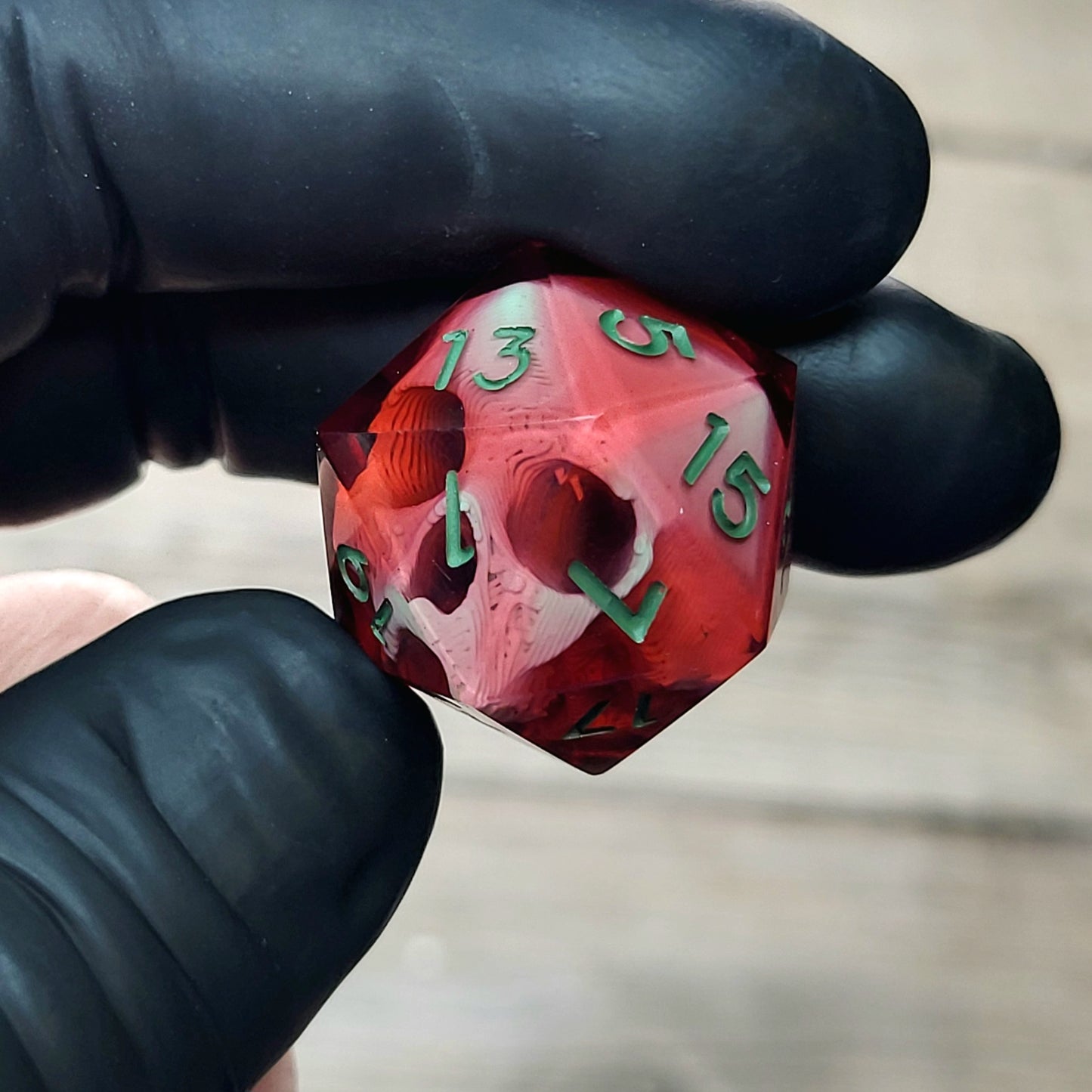 This is a single set of one D20 DnD die with a light green skull inside , red resin and green numbers