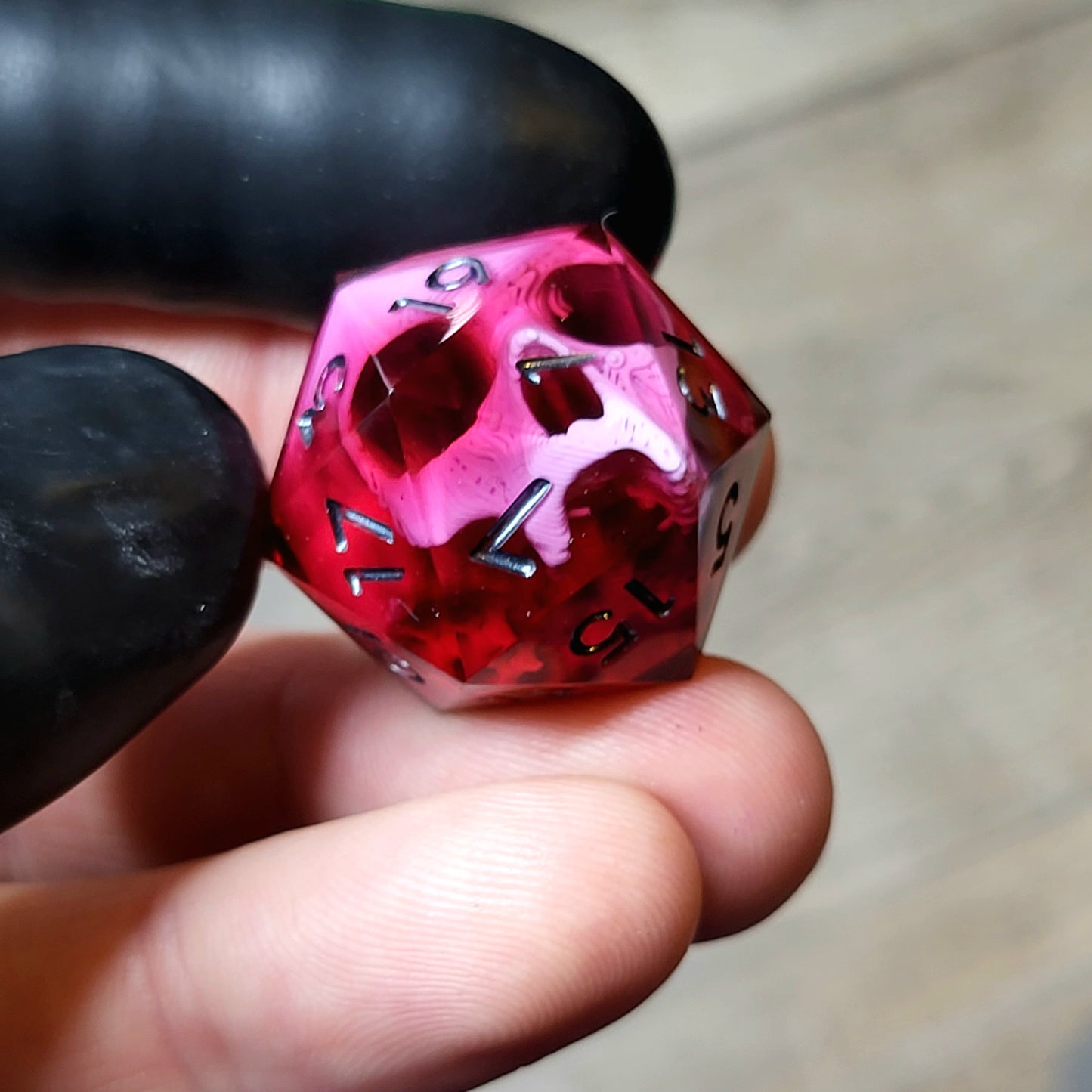 This is a single set of one D20 DND die with a pink skull inside ,red resin and black silver numbers