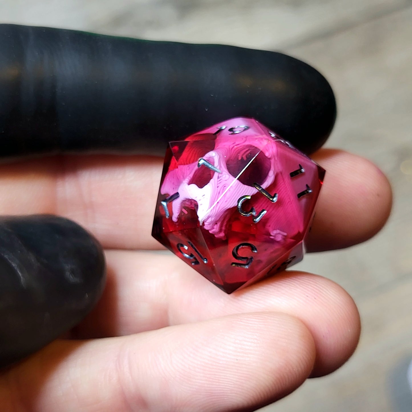 This is a single set of one D20 DND die with a pink skull inside ,red resin and black silver numbers