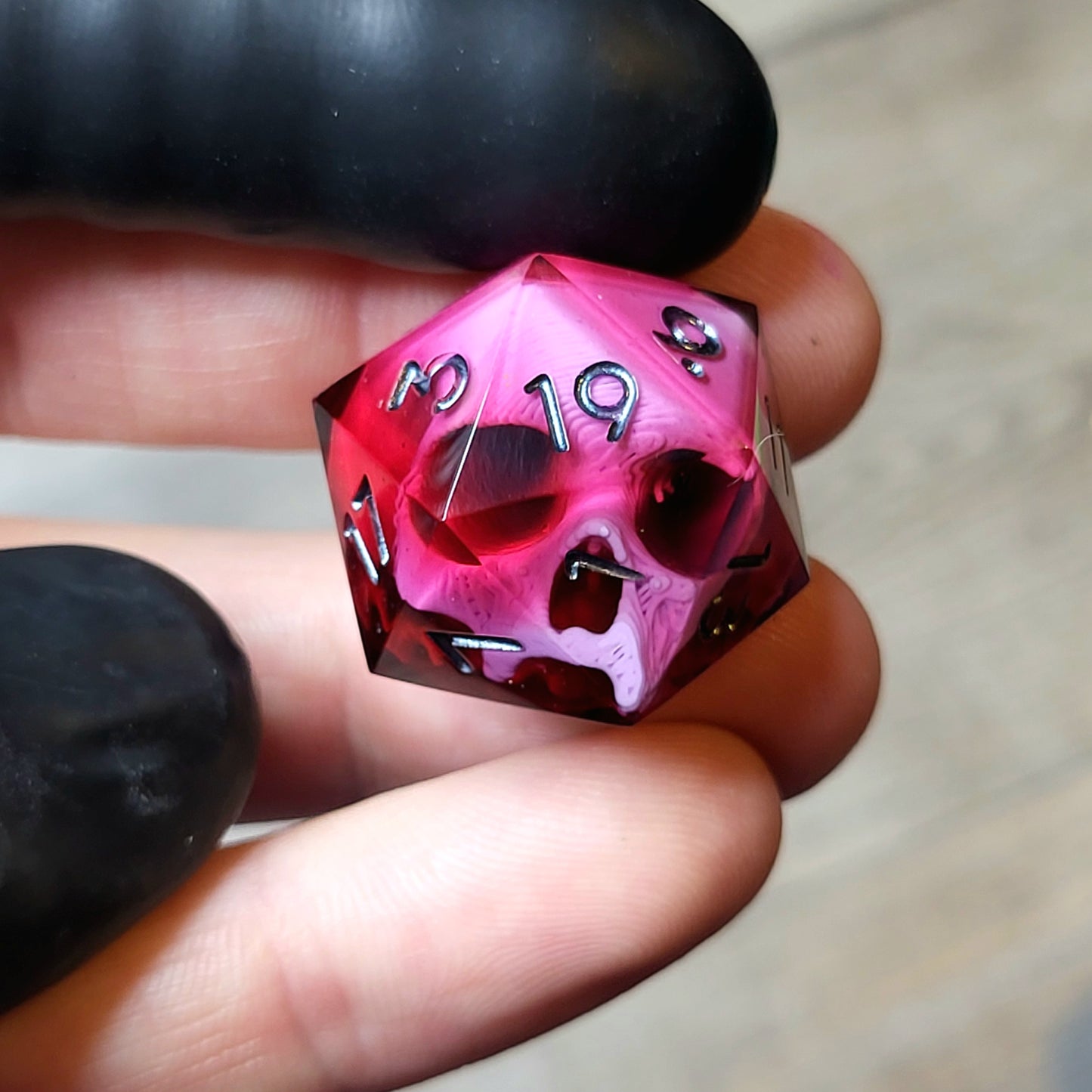 This is a single set of one D20 DND die with a pink skull inside ,red resin and black silver numbers