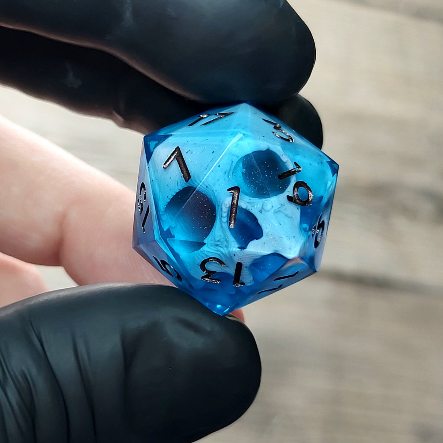 This is a single set of one D20 DnD die with a white skull inside ,blue resin and metal dark numbers