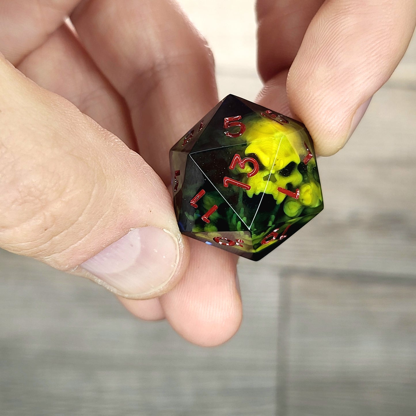 Black resin DnD dice with yellow skull inside and red engraved numbers