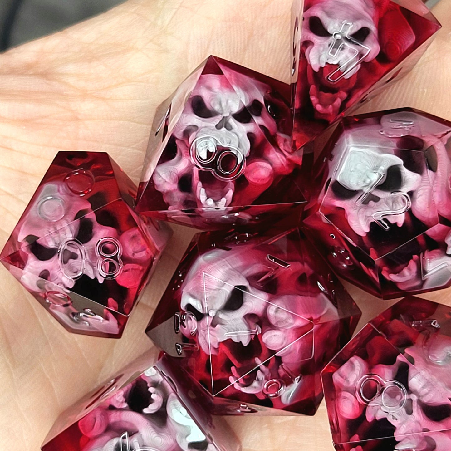 Handmade sharp edge resin dice set with floating skull inclusions in transparent crimson red resin