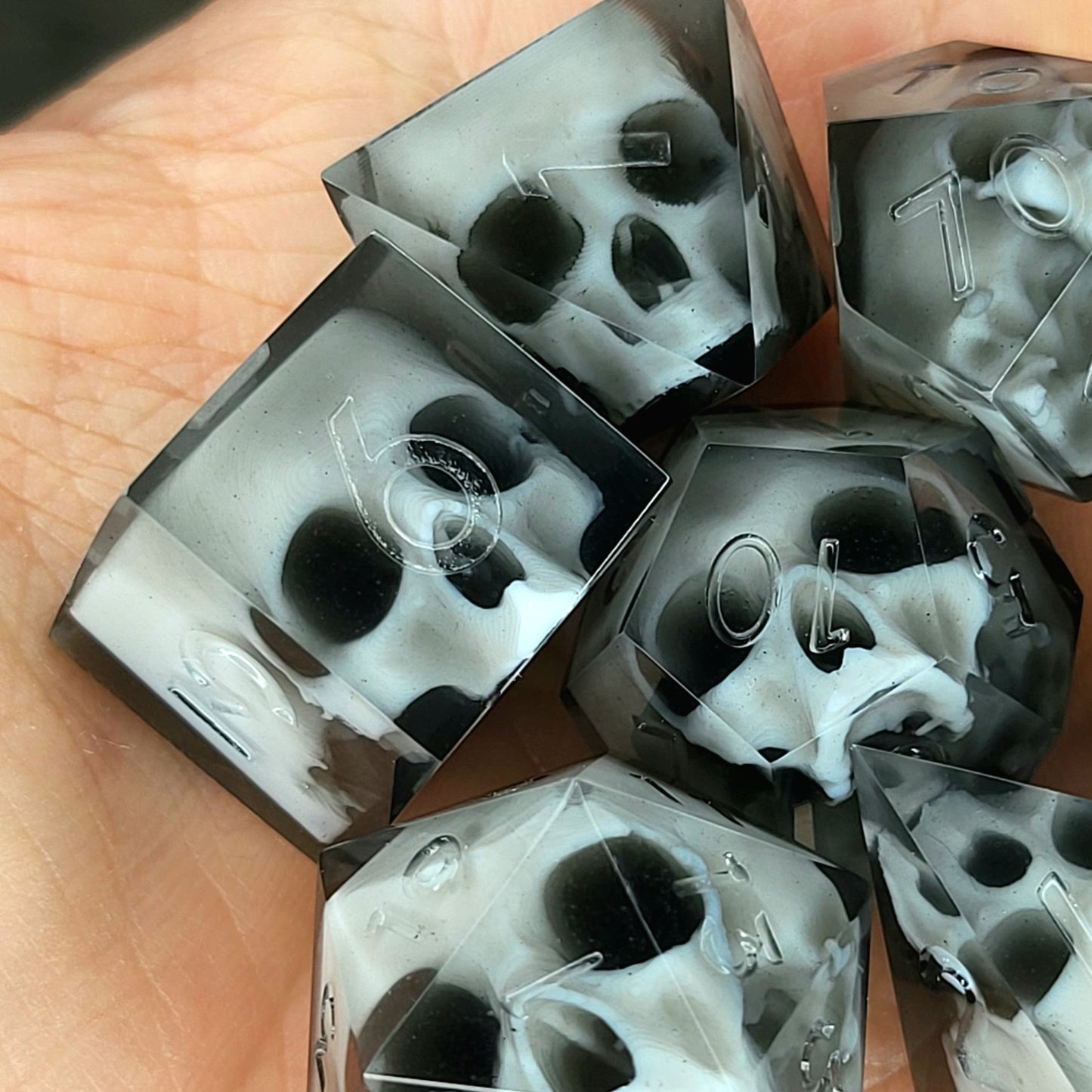 Handmade polyhedral dice set for Dungeons & Dragons (D&D) and tabletop RPGs, crafted in black resin with white skulls embedded inside