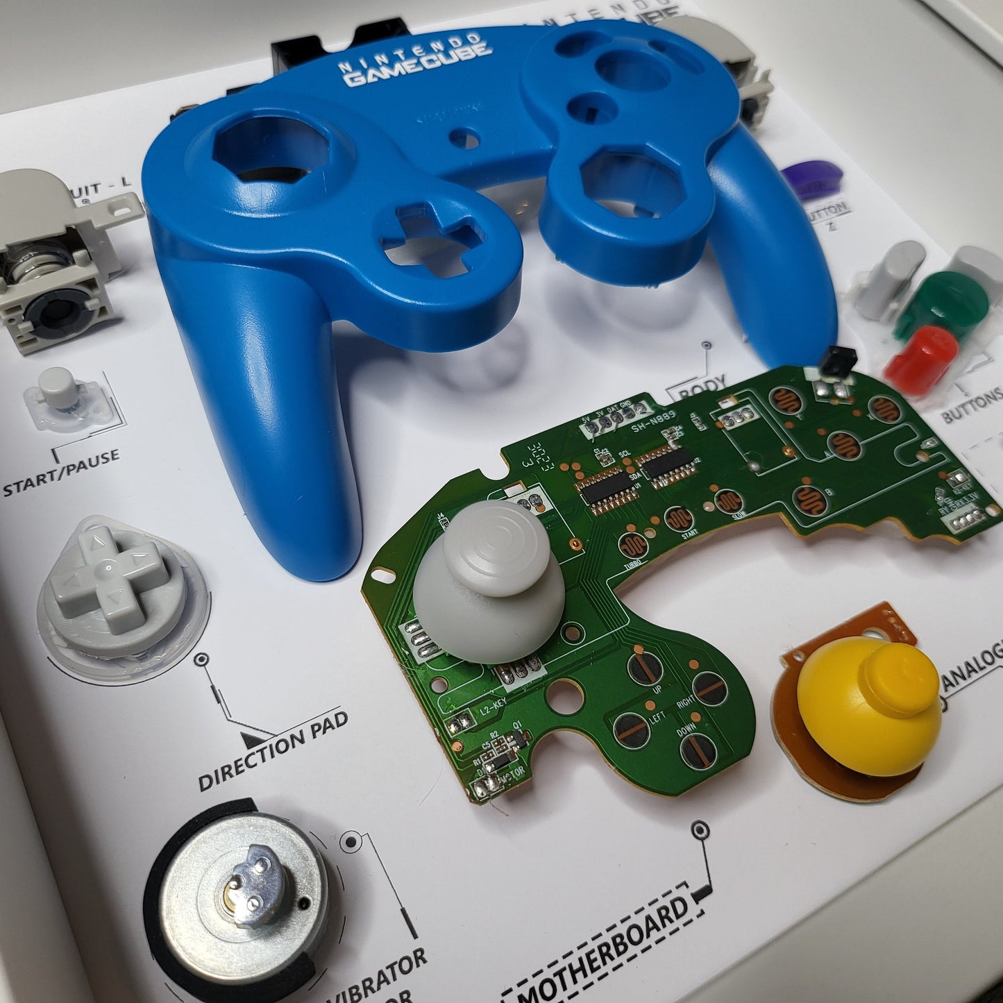 Shadow Box 10x10 with wood frame and polycarbonate glass for wall and Tabletop containing a disassembled controller for Playstation and Nintendo