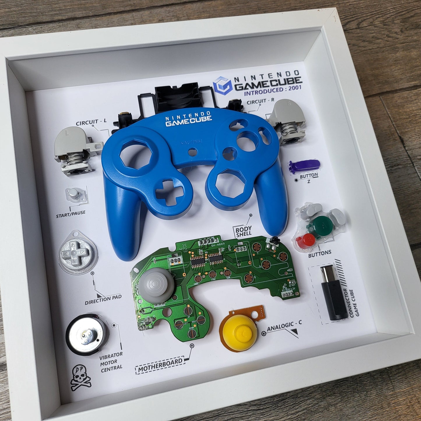 Shadow Box 10x10 with wood frame and polycarbonate glass for wall and Tabletop containing a disassembled controller for Playstation and Nintendo