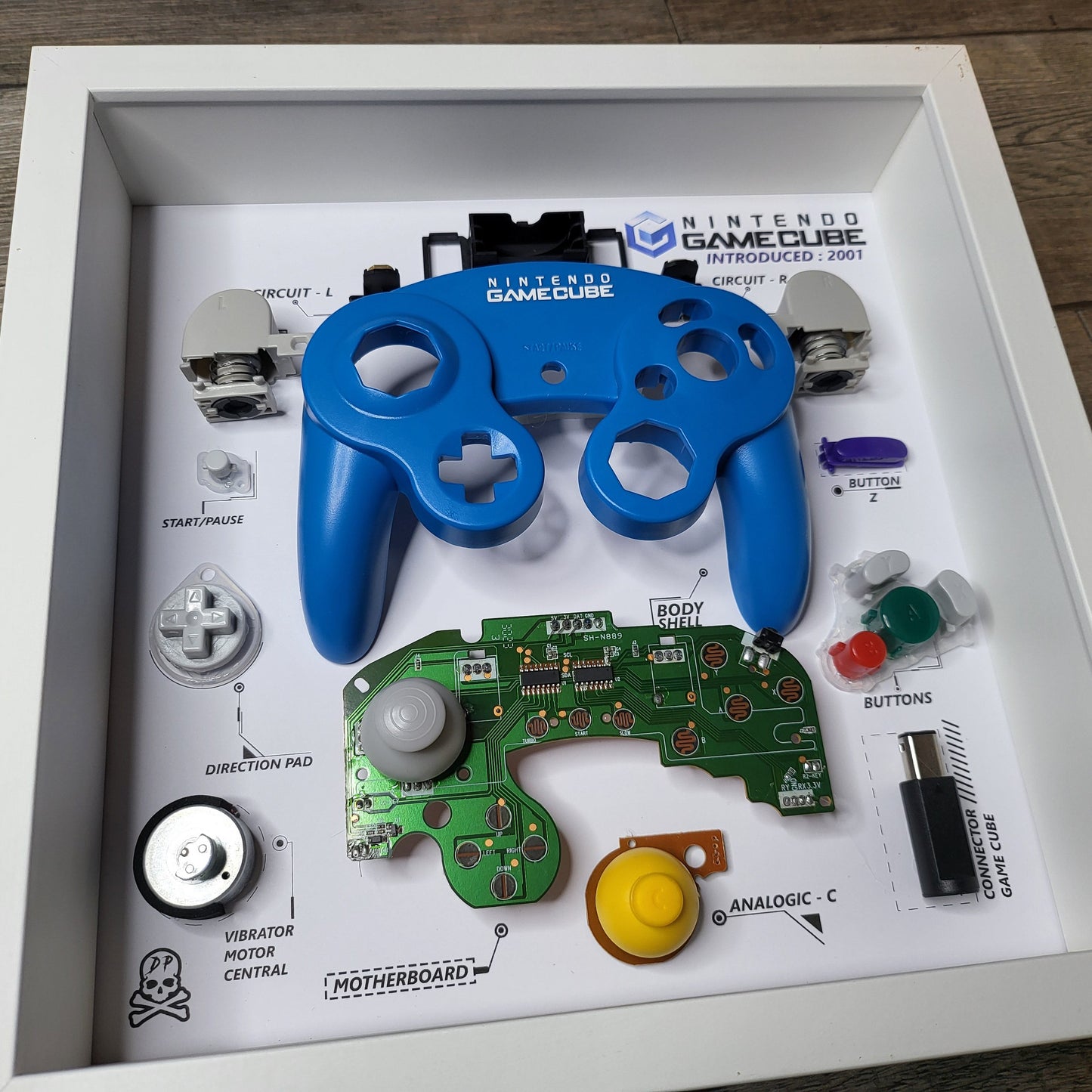 Shadow Box 10x10 with wood frame and polycarbonate glass for wall and Tabletop containing a disassembled controller for Playstation and Nintendo