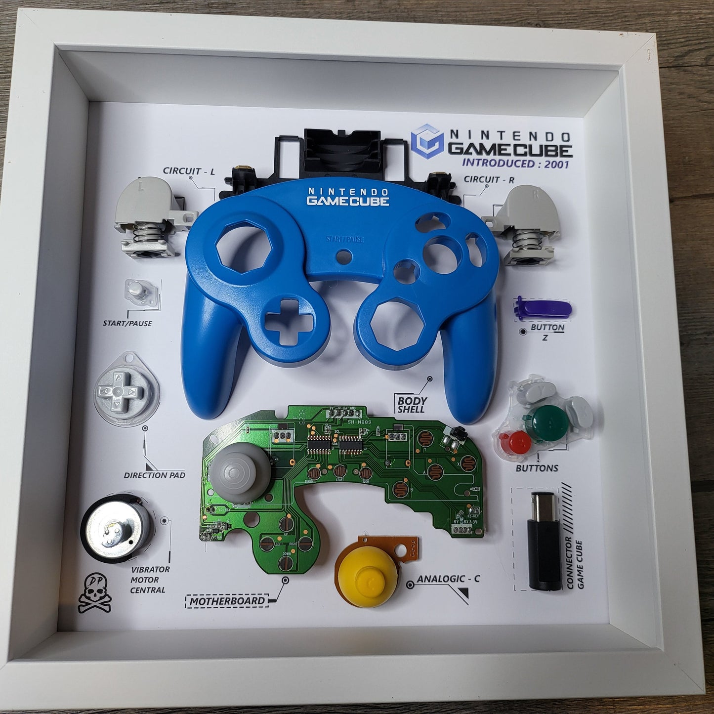 Shadow Box 10x10 with wood frame and polycarbonate glass for wall and Tabletop containing a disassembled controller for Playstation and Nintendo