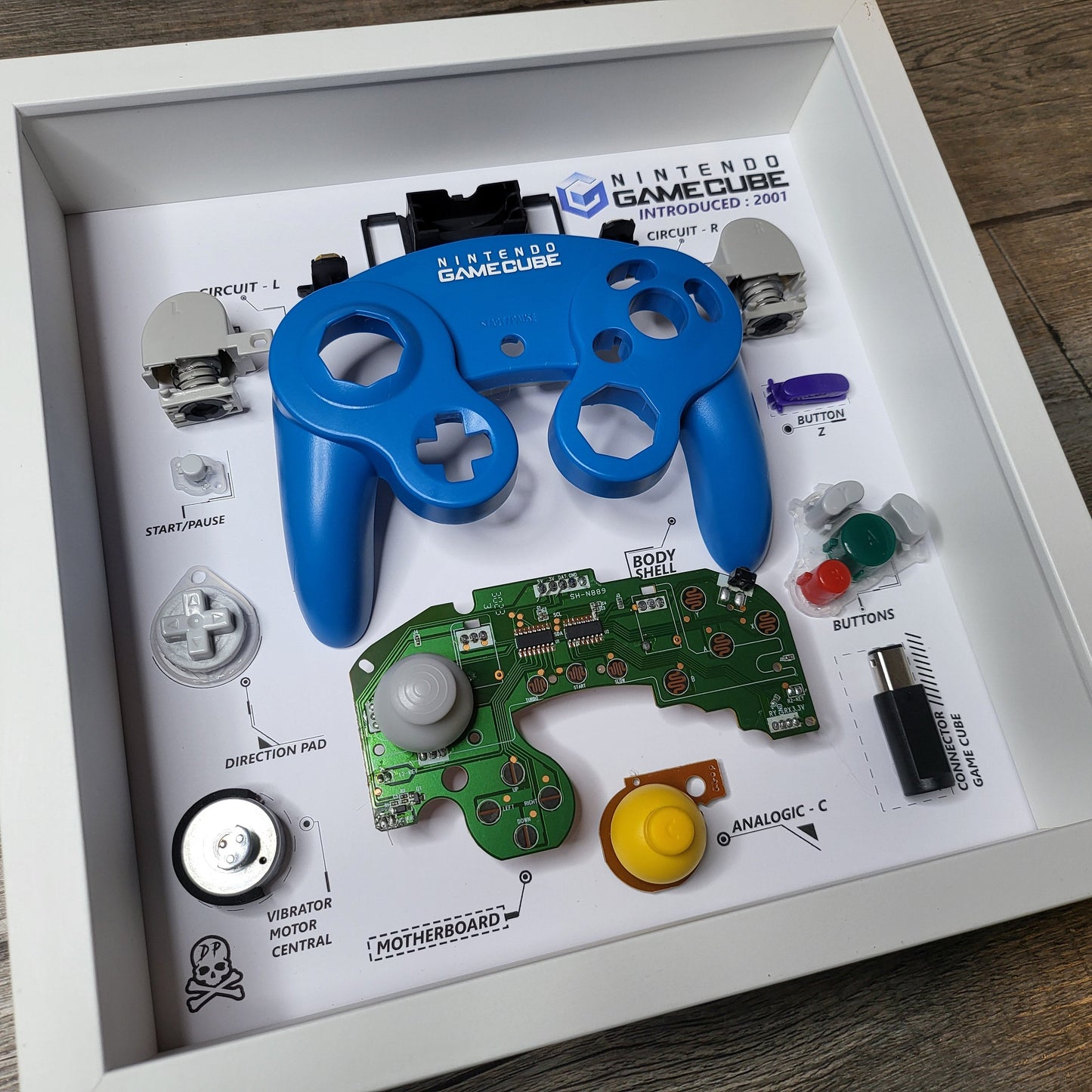 Shadow Box 10x10 with wood frame and polycarbonate glass for wall and Tabletop containing a disassembled controller for Playstation and Nintendo