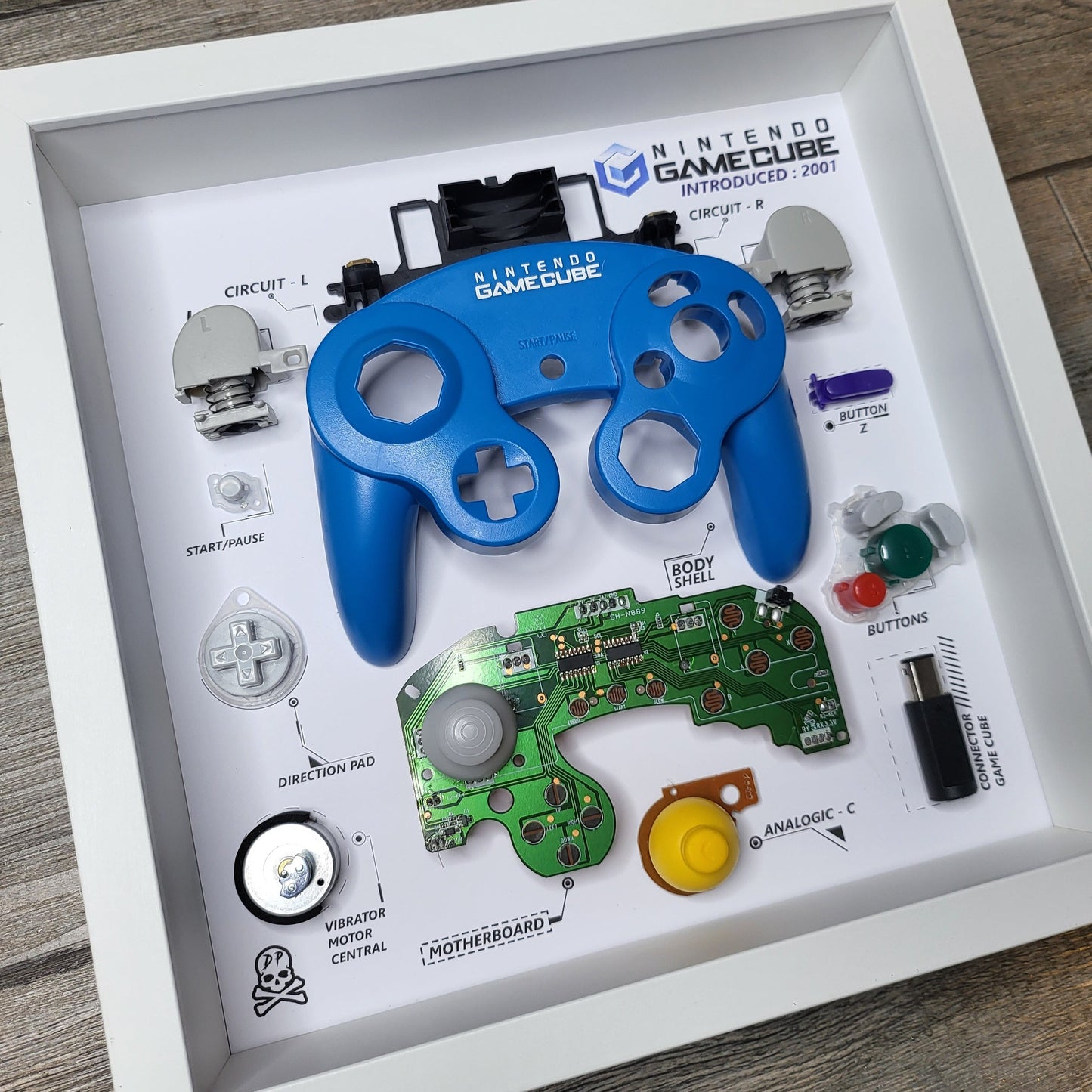 Shadow Box 10x10 with wood frame and polycarbonate glass for wall and Tabletop containing a disassembled controller for Playstation and Nintendo