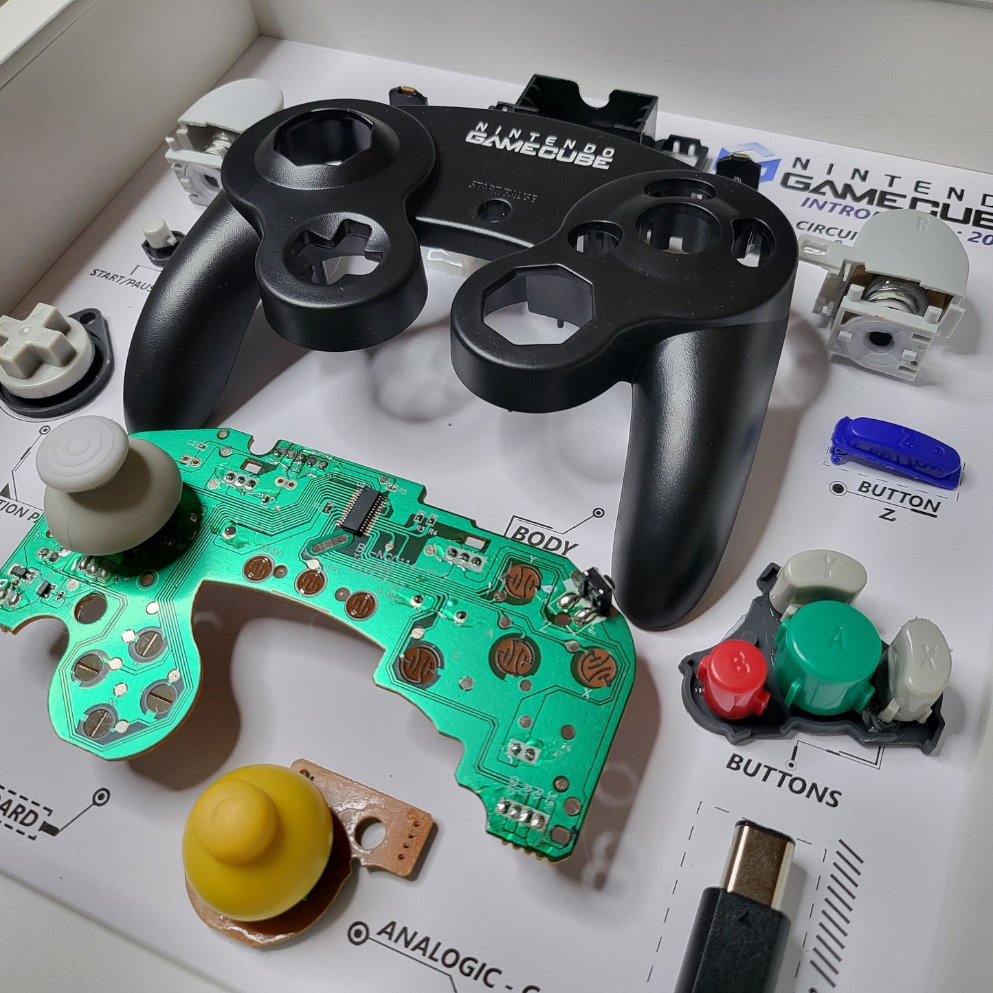 Shadow Box 10x10 with wood frame and polycarbonate glass for wall and Tabletop containing a disassembled controller for Playstation and Nintendo