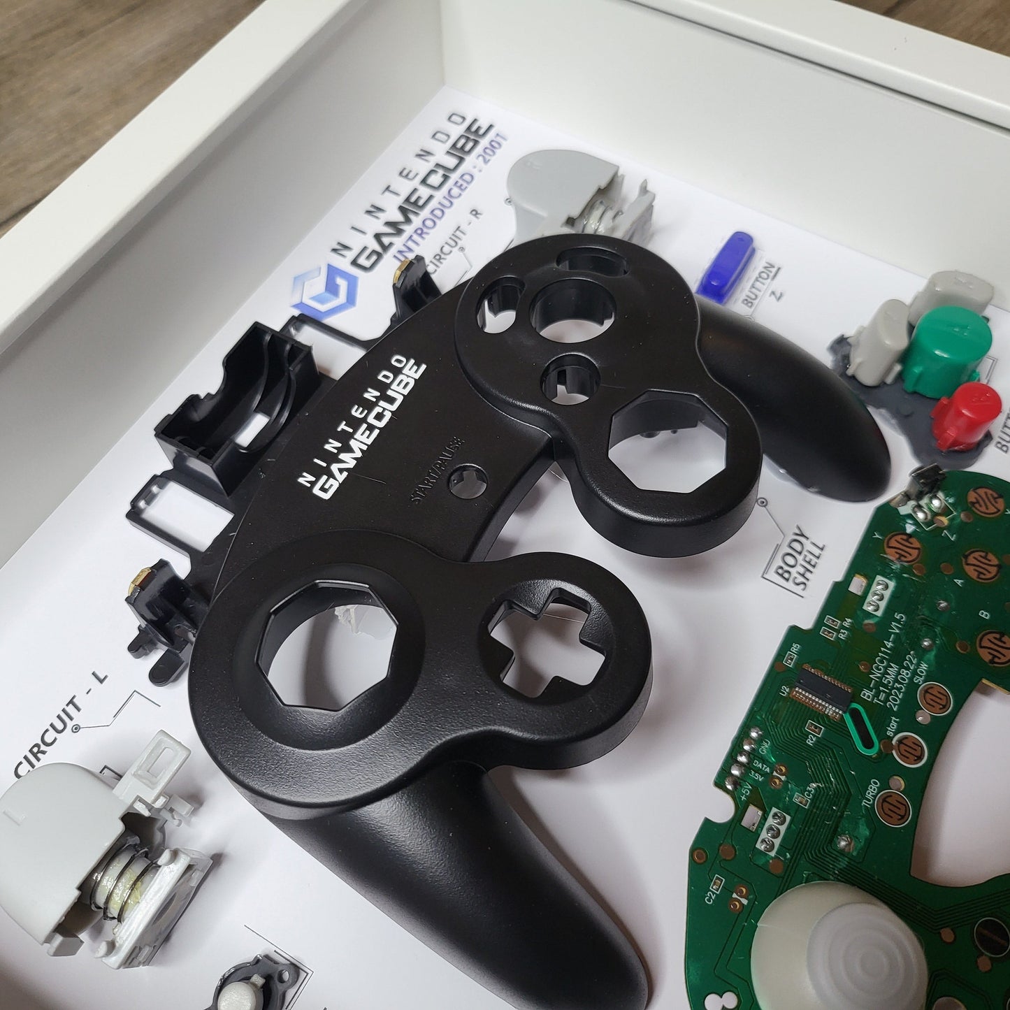 Shadow Box 10x10 with wood frame and polycarbonate glass for wall and Tabletop containing a disassembled controller for Playstation and Nintendo