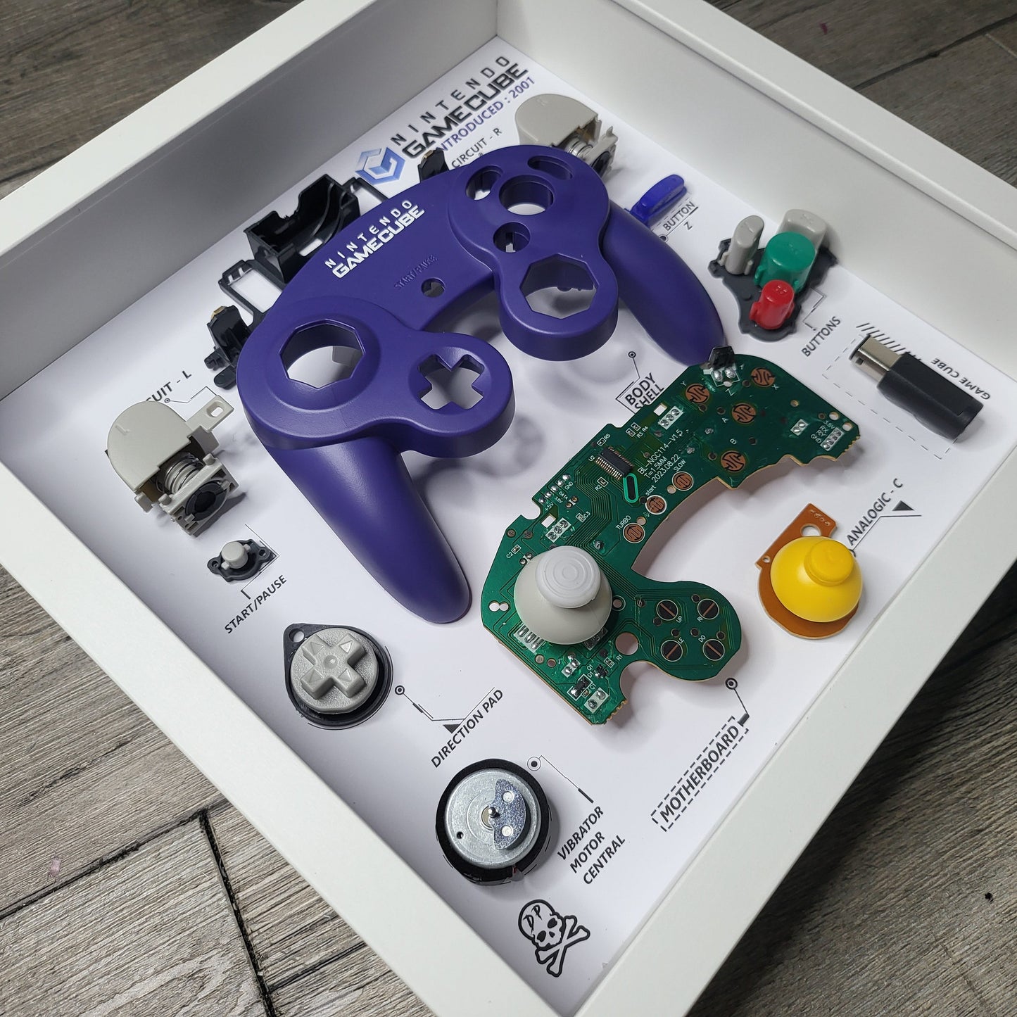 Shadow Box 10x10 with wood frame and polycarbonate glass for wall and Tabletop containing a disassembled controller for Playstation and Nintendo