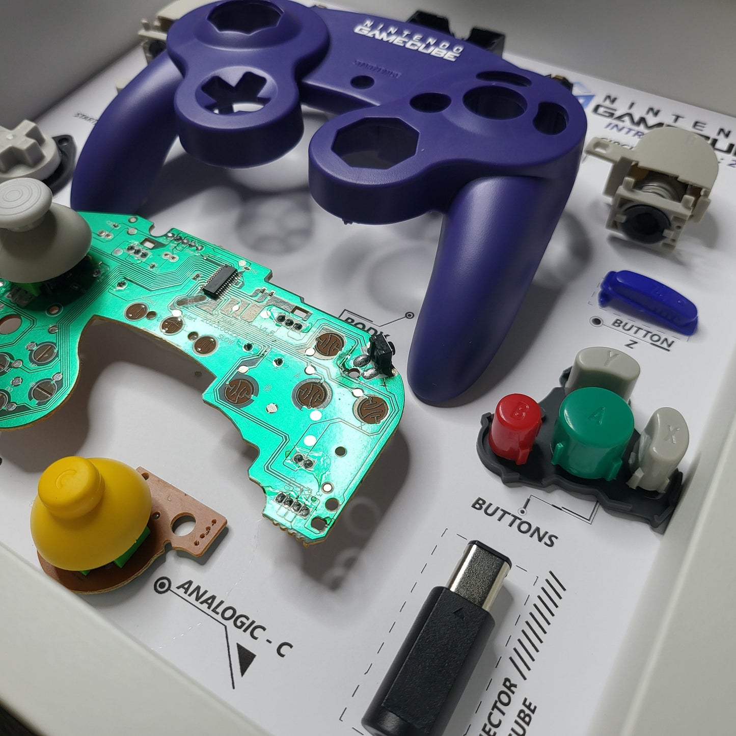 Shadow Box 10x10 with wood frame and polycarbonate glass for wall and Tabletop containing a disassembled controller for Playstation and Nintendo