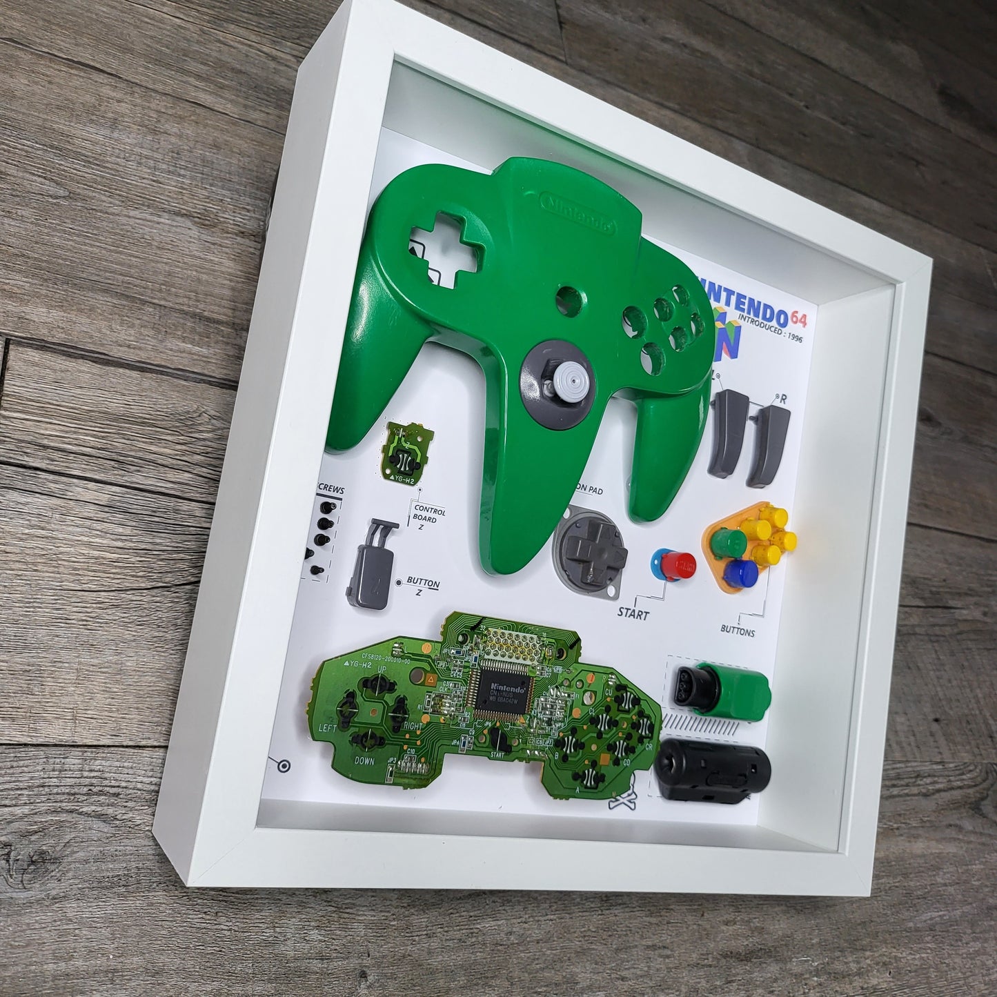 Shadow Box 10x10 with wood frame and polycarbonate glass for wall and Tabletop containing a disassembled controller for Playstation and Nintendo