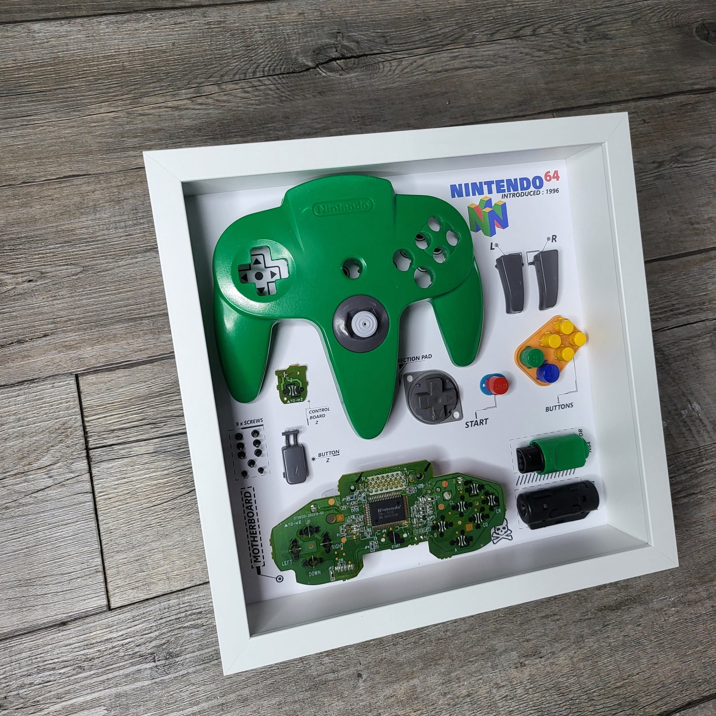 Shadow Box 10x10 with wood frame and polycarbonate glass for wall and Tabletop containing a disassembled controller for Playstation and Nintendo