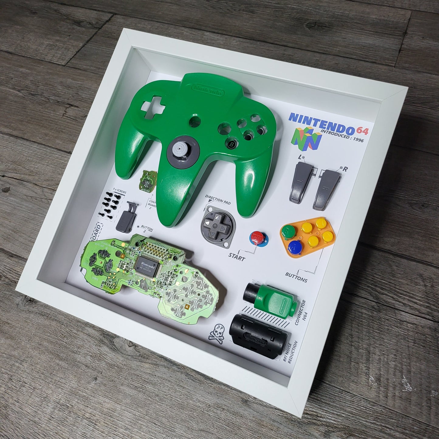Shadow Box 10x10 with wood frame and polycarbonate glass for wall and Tabletop containing a disassembled controller for Playstation and Nintendo