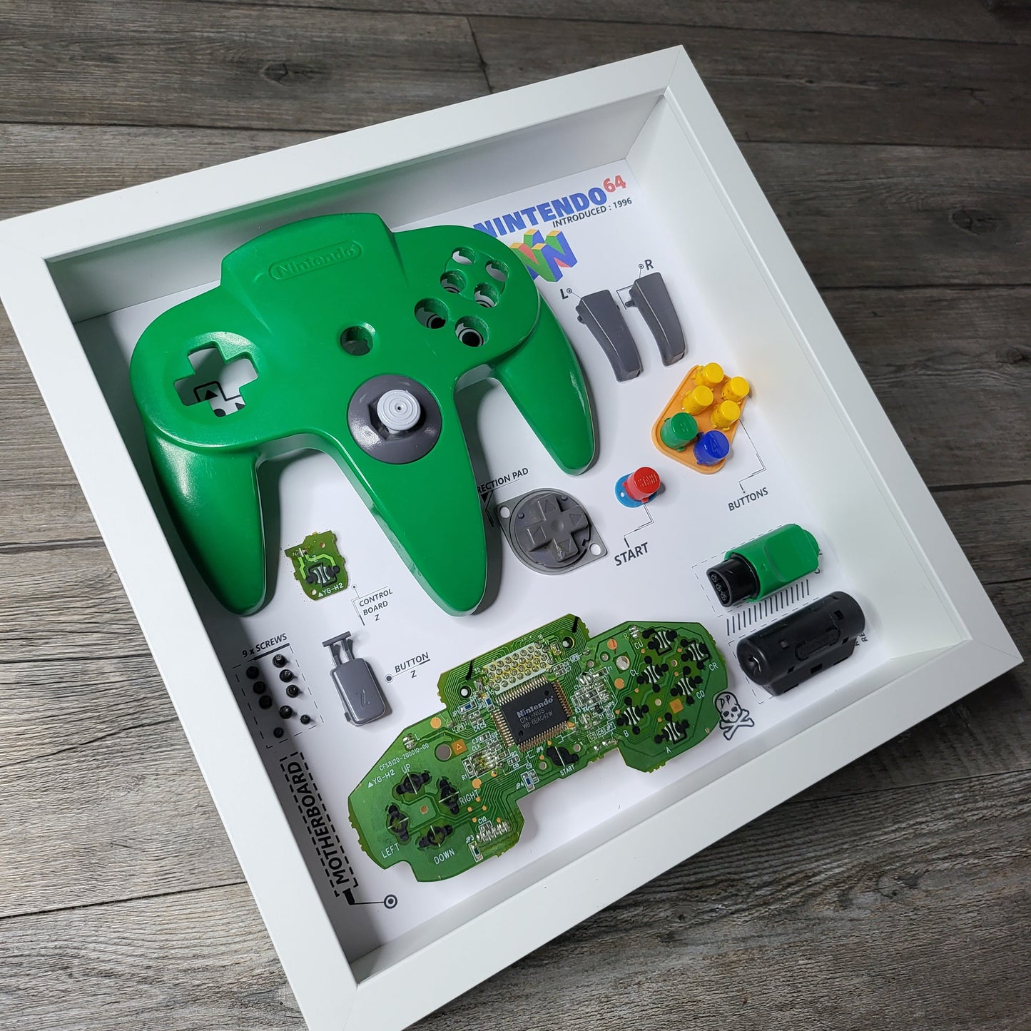 Shadow Box 10x10 with wood frame and polycarbonate glass for wall and Tabletop containing a disassembled controller for Playstation and Nintendo