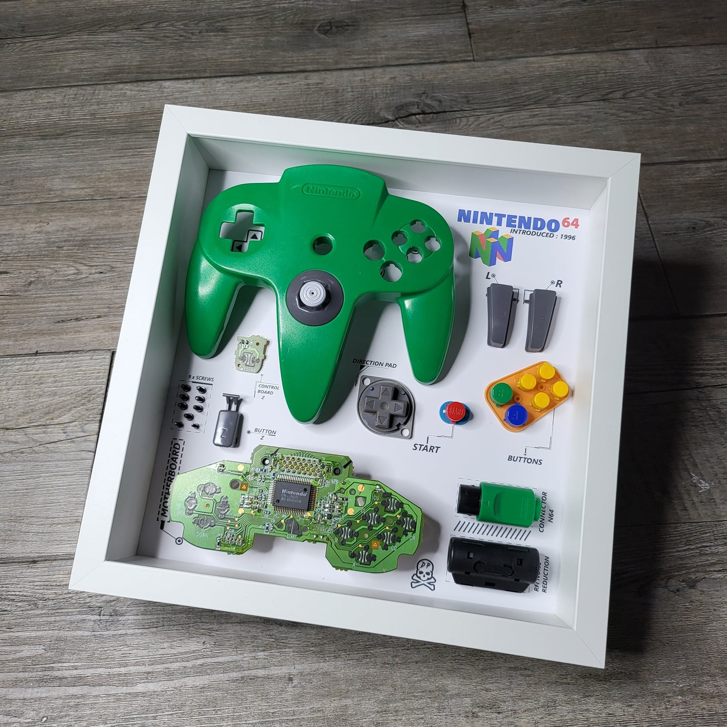 Shadow Box 10x10 with wood frame and polycarbonate glass for wall and Tabletop containing a disassembled controller for Playstation and Nintendo