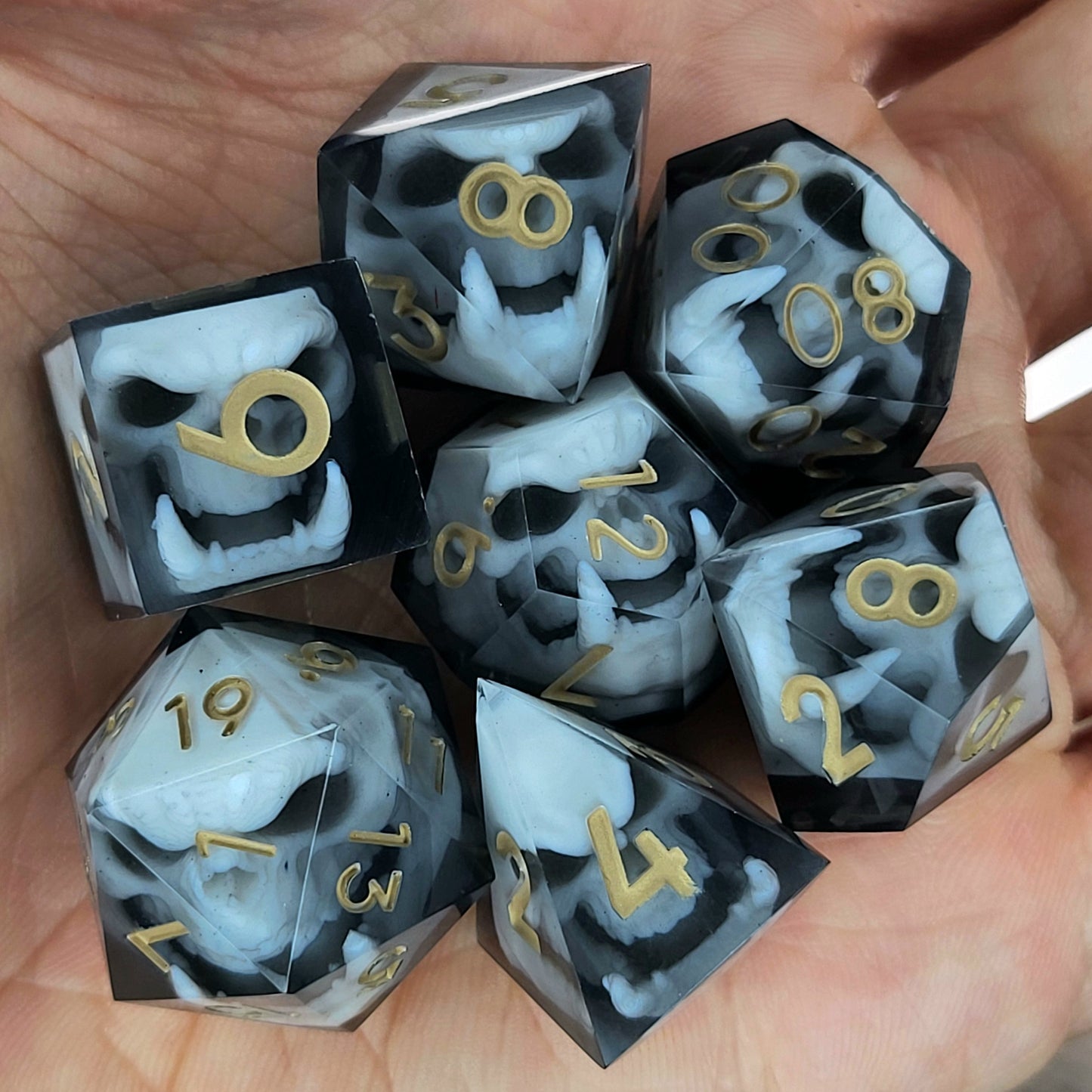 Black and white resin dice set featuring detailed orc skulls with gold numbers, fantasy RPG dice for DnD and tabletop roleplaying games