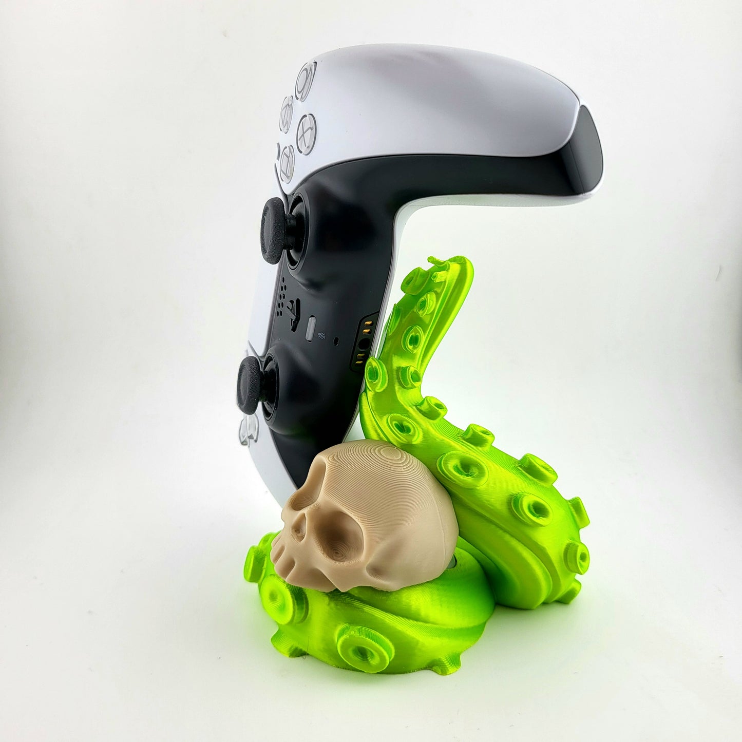 Stylish PS5 controller stand featuring a skull design with green tentacles, perfect for gamers' setups. The stand is totally handcrafted and 3D printed following a self-made sophisticated design. The controller holder can be put on the table to display your controller anytime.