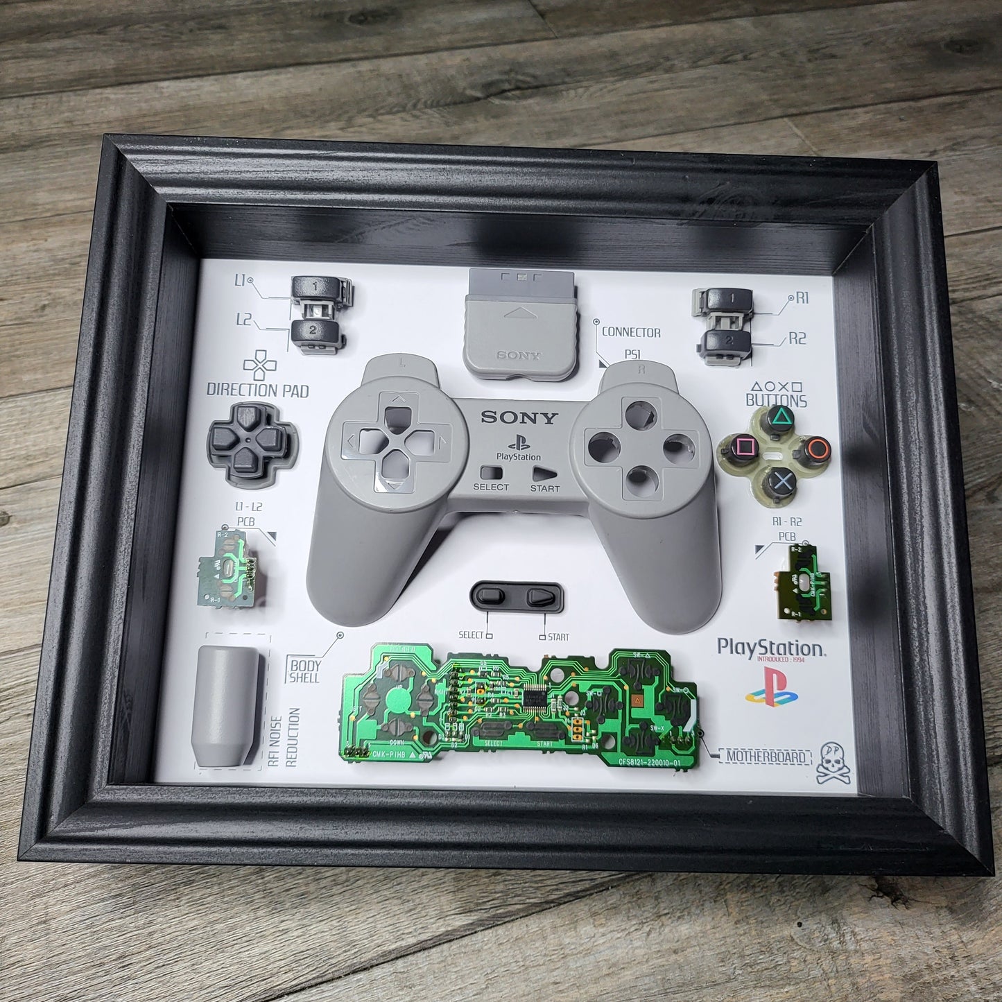 Shadow Box 10x10 with wood frame and polycarbonate glass for wall and Tabletop containing a disassembled controller for Playstation and Nintendo