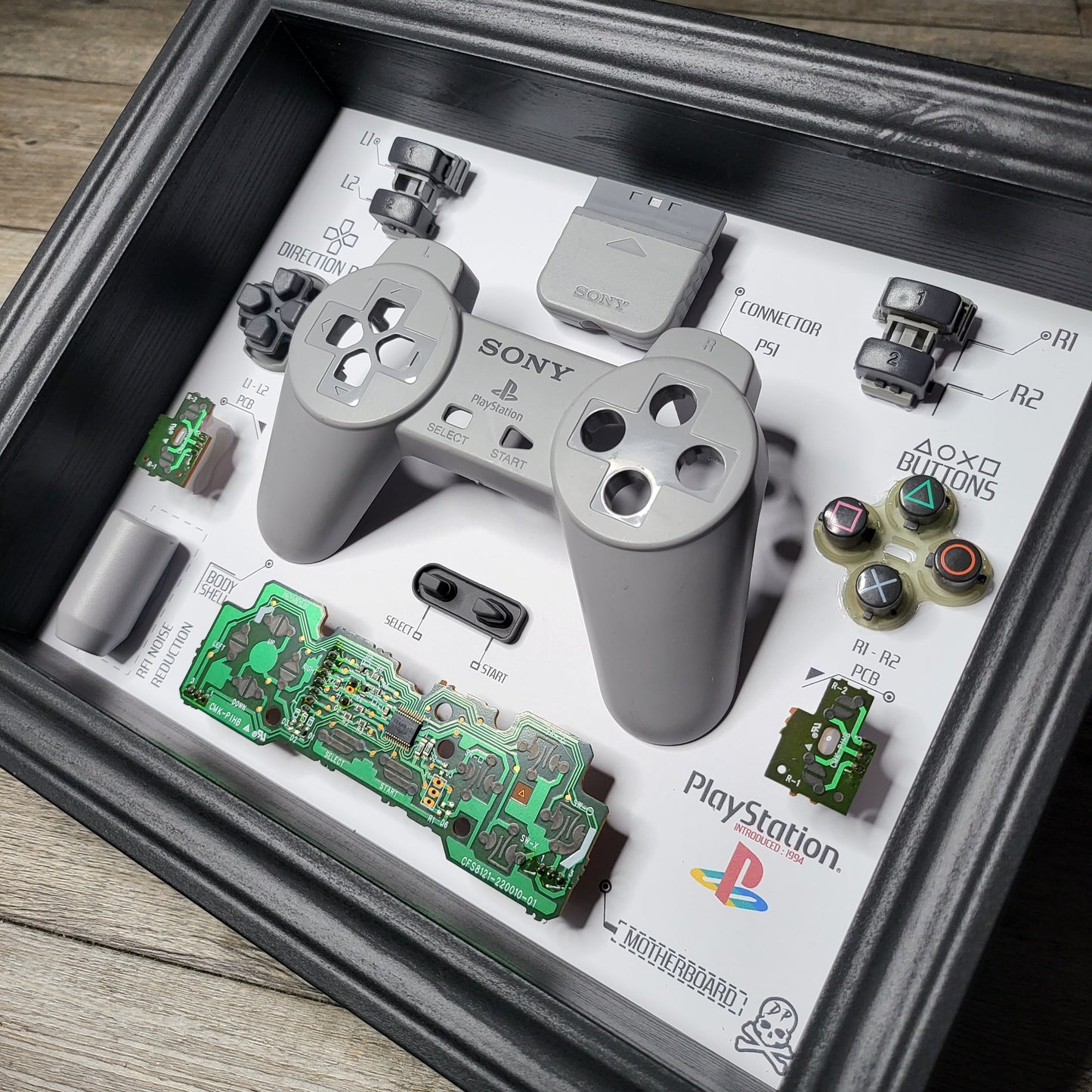Shadow Box 10x10 with wood frame and polycarbonate glass for wall and Tabletop containing a disassembled controller for Playstation and Nintendo