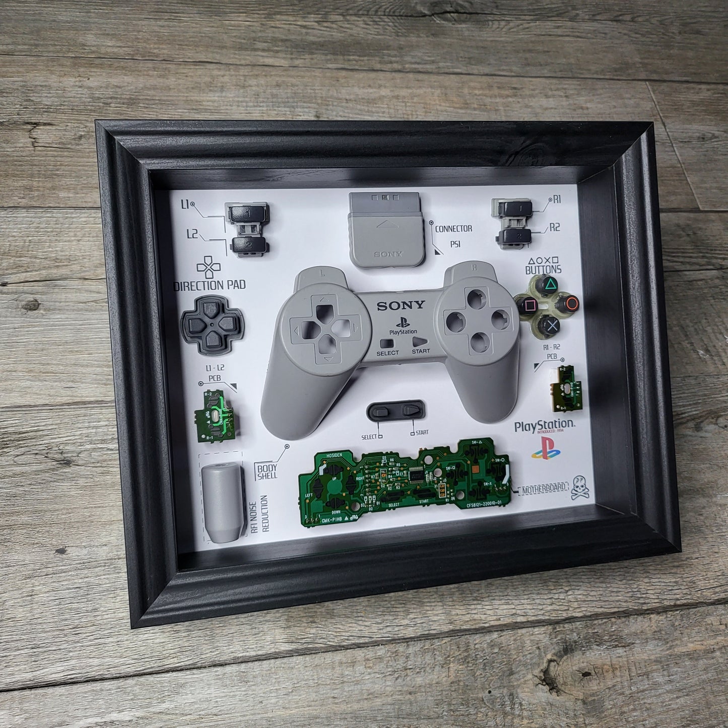 Shadow Box 10x10 with wood frame and polycarbonate glass for wall and Tabletop containing a disassembled controller for Playstation and Nintendo