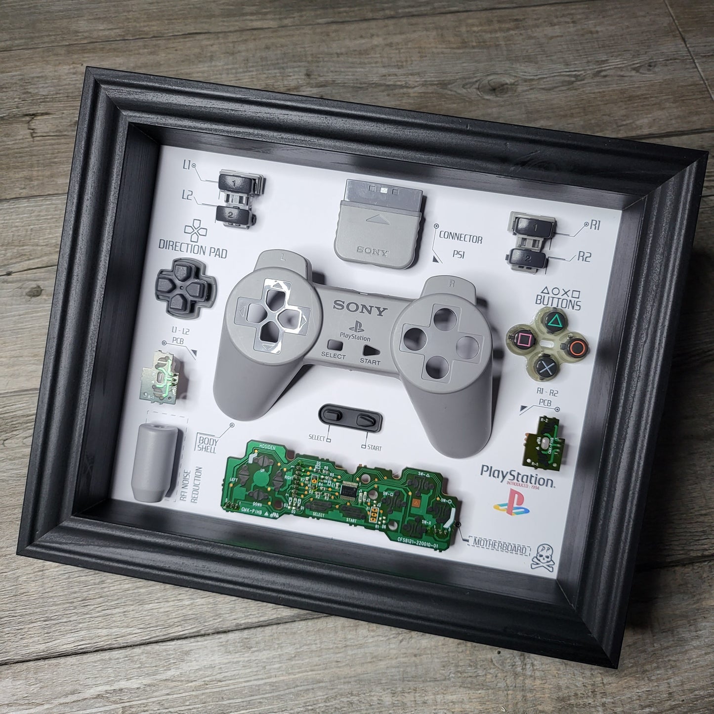 Shadow Box 10x10 with wood frame and polycarbonate glass for wall and Tabletop containing a disassembled controller for Playstation and Nintendo