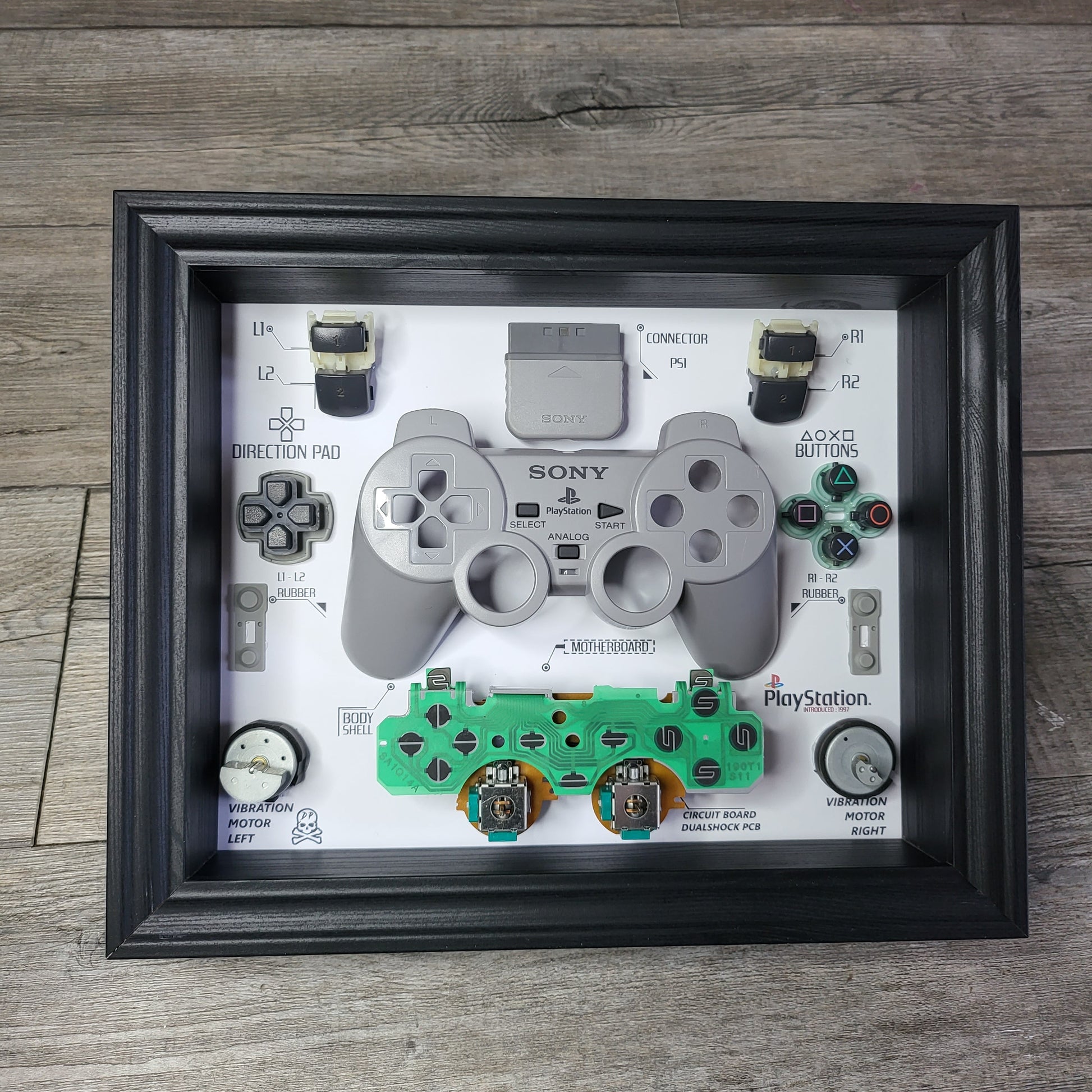 Shadow Box 10x10 with wood frame and polycarbonate glass for wall and Tabletop containing a disassembled controller for Playstation and Nintendo