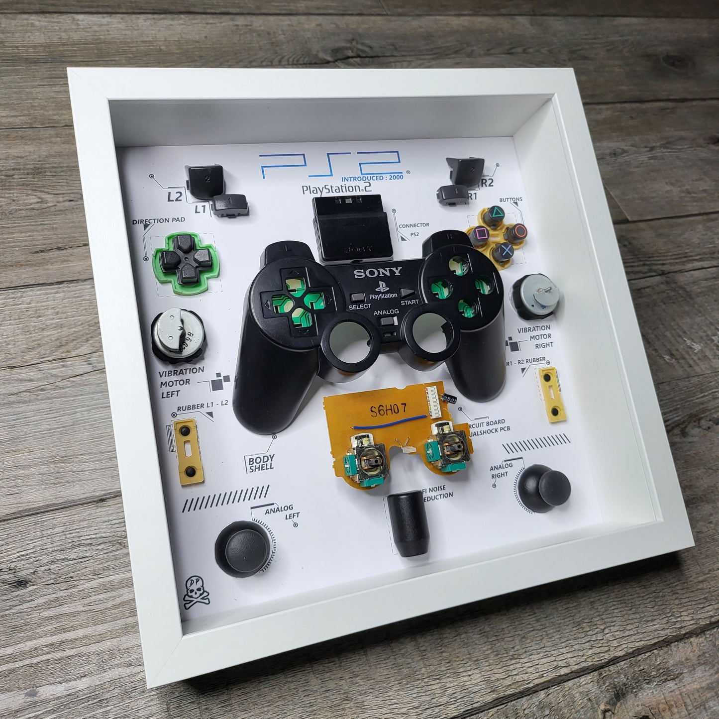 Shadow Box 10x10 with wood frame and polycarbonate glass for wall and Tabletop containing a disassembled controller for Playstation and Nintendo