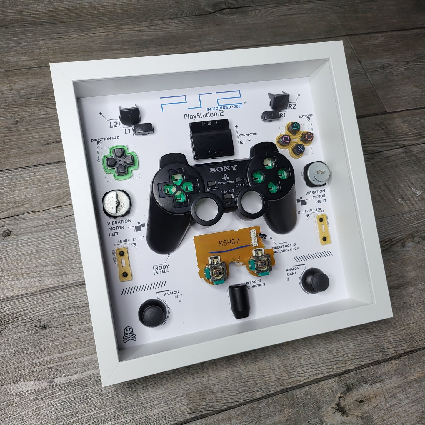 Shadow Box 10x10 with wood frame and polycarbonate glass for wall and Tabletop containing a disassembled controller for Playstation and Nintendo
