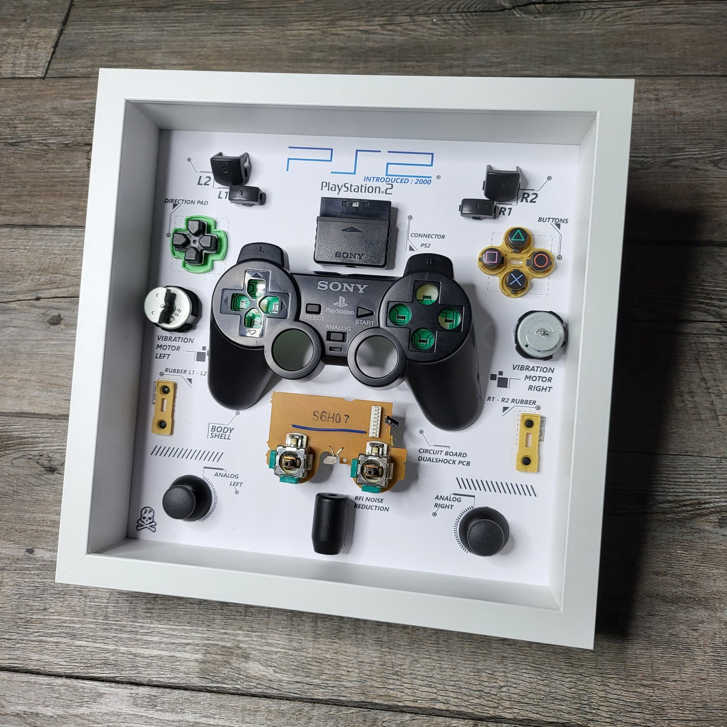 Shadow Box 10x10 with wood frame and polycarbonate glass for wall and Tabletop containing a disassembled controller for Playstation and Nintendo