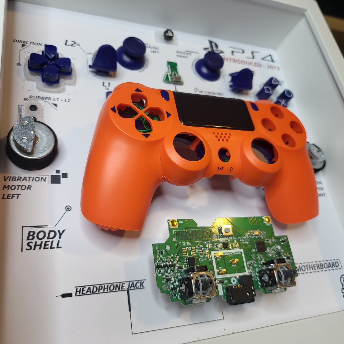 Shadow Box 10x10 with wood frame and polycarbonate glass for wall and Tabletop containing a disassembled controller for Playstation and Nintendo