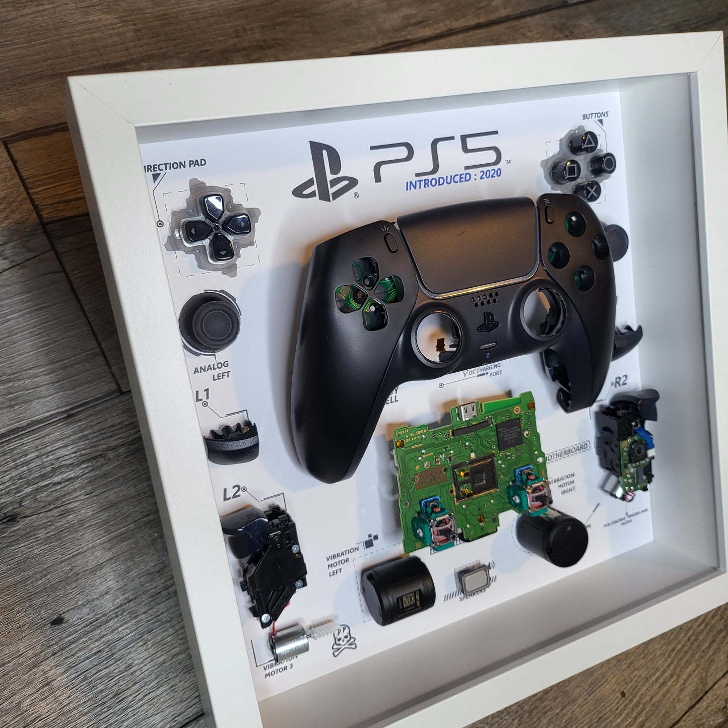 Shadow Box 10x10 with wood frame and polycarbonate glass for wall and Tabletop containing a disassembled controller for Playstation and Nintendo