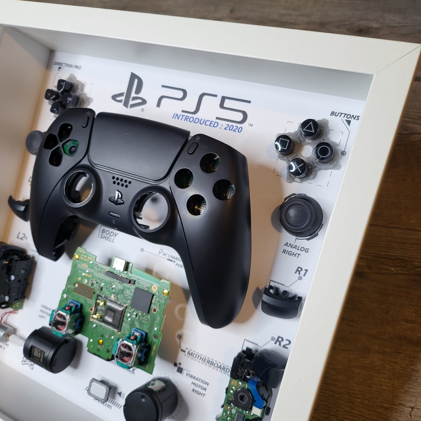 Shadow Box 10x10 with wood frame and polycarbonate glass for wall and Tabletop containing a disassembled controller for Playstation and Nintendo