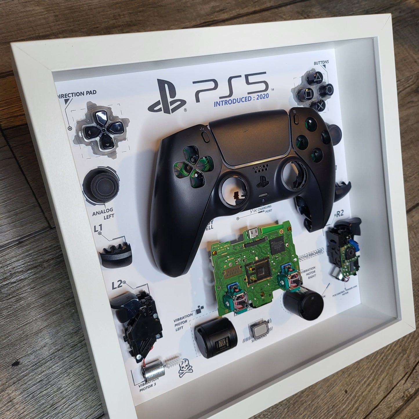 Shadow Box 10x10 with wood frame and polycarbonate glass for wall and Tabletop containing a disassembled controller for Playstation and Nintendo