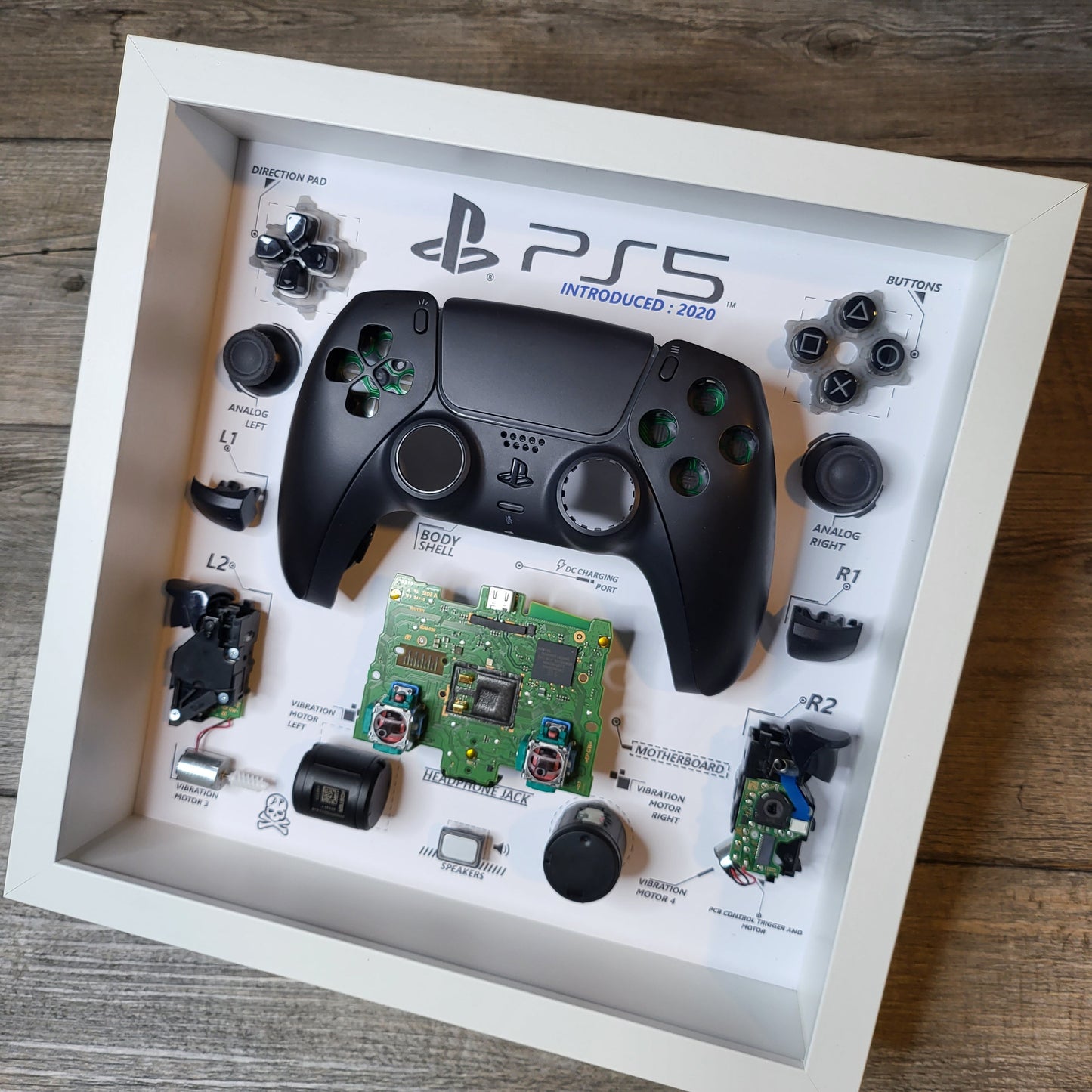 Shadow Box 10x10 with wood frame and polycarbonate glass for wall and Tabletop containing a disassembled controller for Playstation and Nintendo