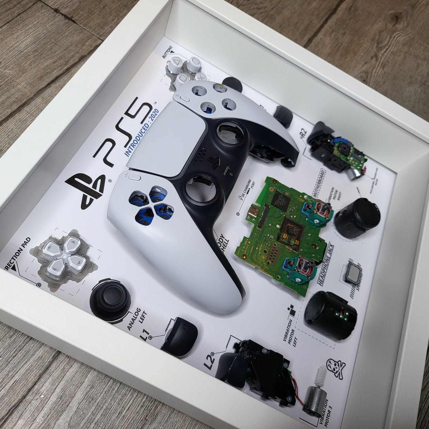 Shadow Box 10x10 with wood frame and polycarbonate glass for wall and Tabletop containing a disassembled controller for Playstation and Nintendo
